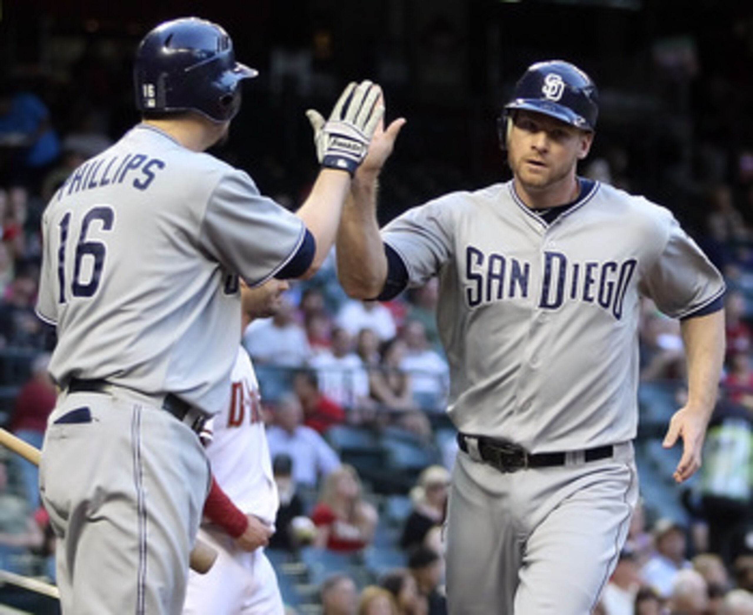PHOENIX, AZ - MAY 16:  Chase Headley #7 of the San Diego Padres high fives teammate Kyle Phillips #16 after scoring a first inning run against the Arizona Diamondbacks during the Major League Baseball game at Chase Field on May 16, 2011 in Phoenix, Arizon