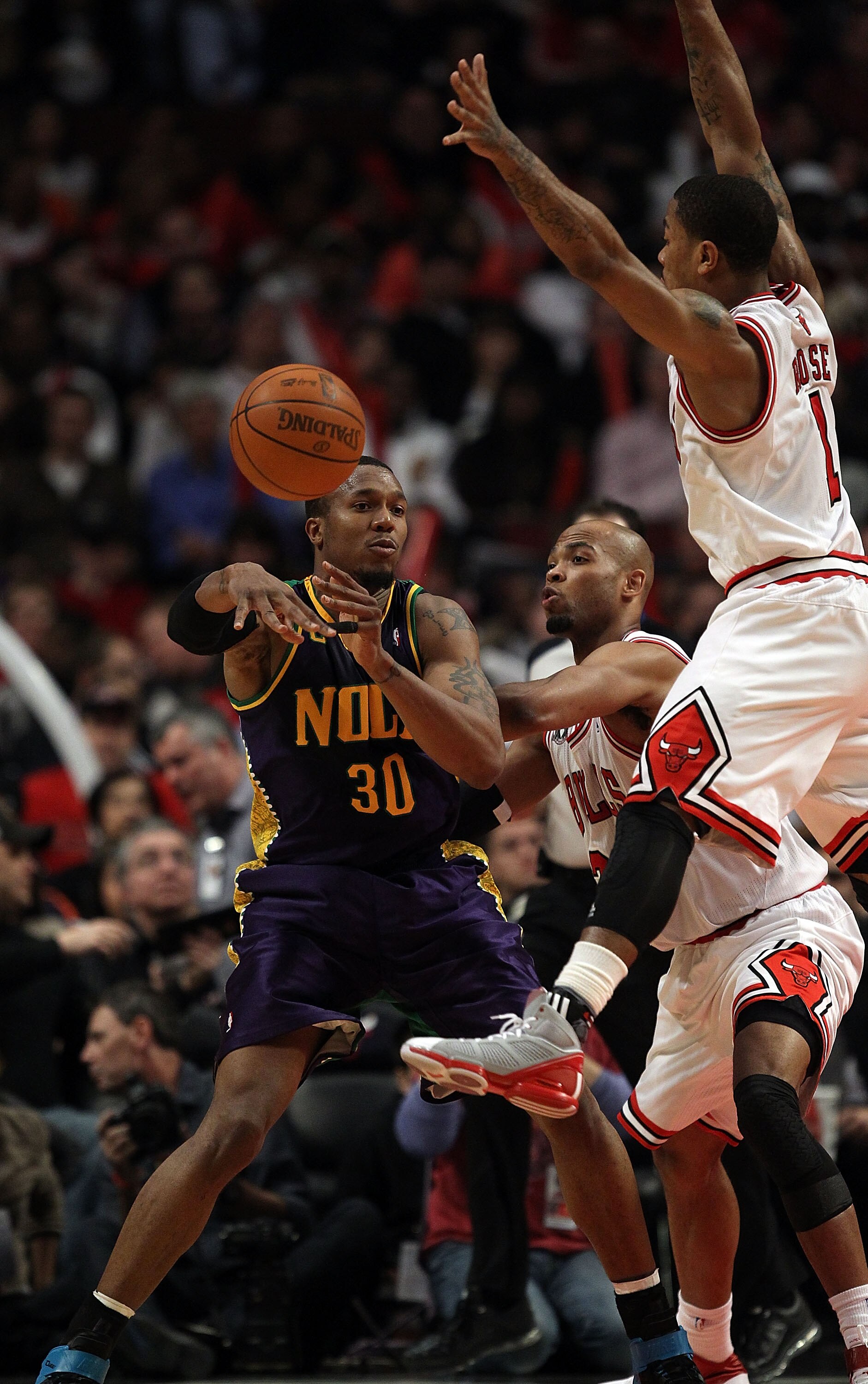 CHICAGO, IL - MARCH 07: David West #30 of the New Orleans Hornets passes the ball as Derrick Rose #1 of the Chicago Bulls leaps to try for the block at the United Center on March 7, 2011 in Chicago, Illinois. The Bulls defeated the Hornets 85-77. NOTE TO 