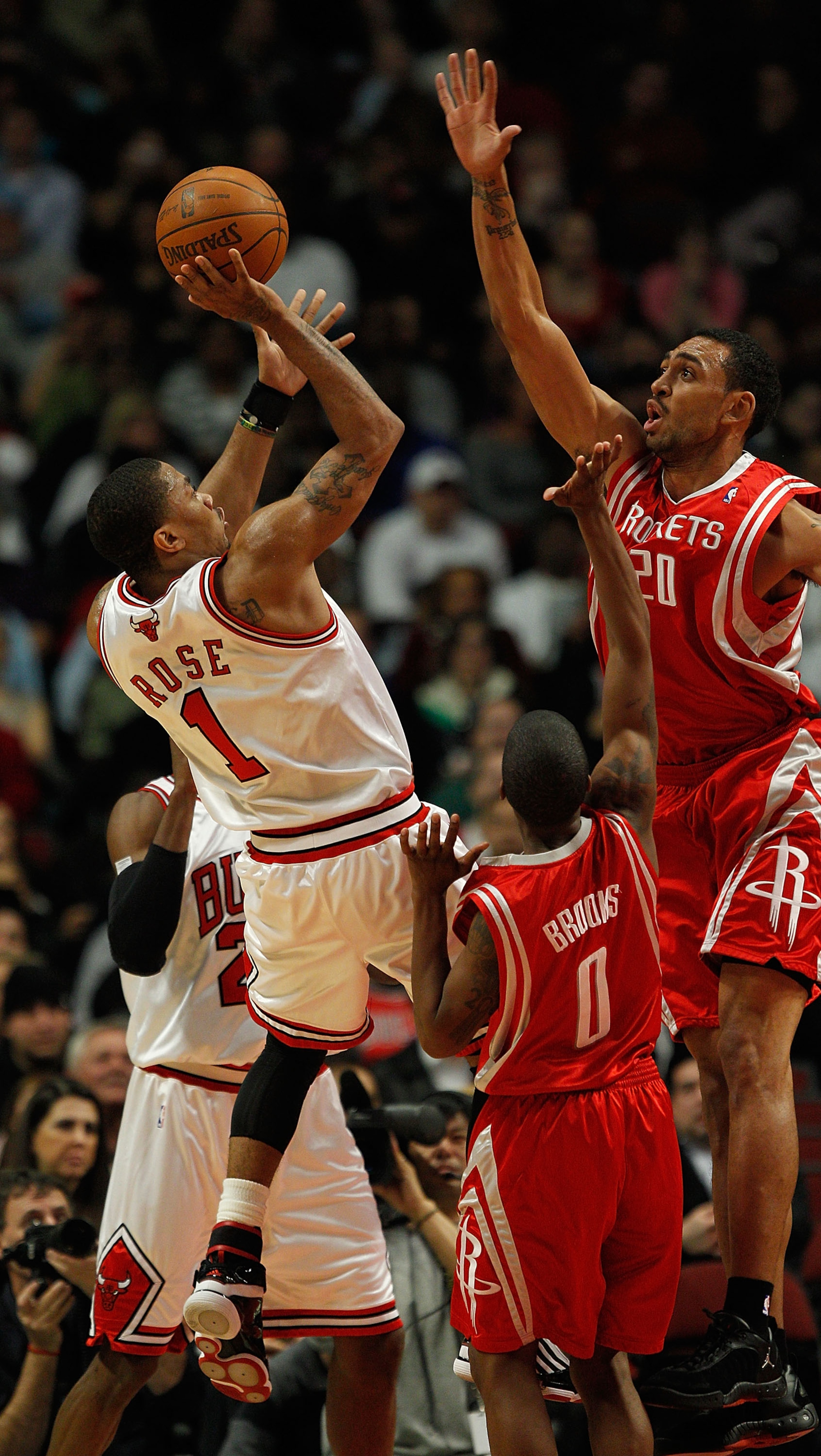 CHICAGO - MARCH 22: Derrick Rose #1 of the Chicago Bulls puts up a shot against Aaron Brooks #0 and Jared Jefferies #20 of the Houston Rockets at the United Center on March 22, 2010 in Chicago, Illinois. NOTE TO USER: User expressly acknowledges and agree