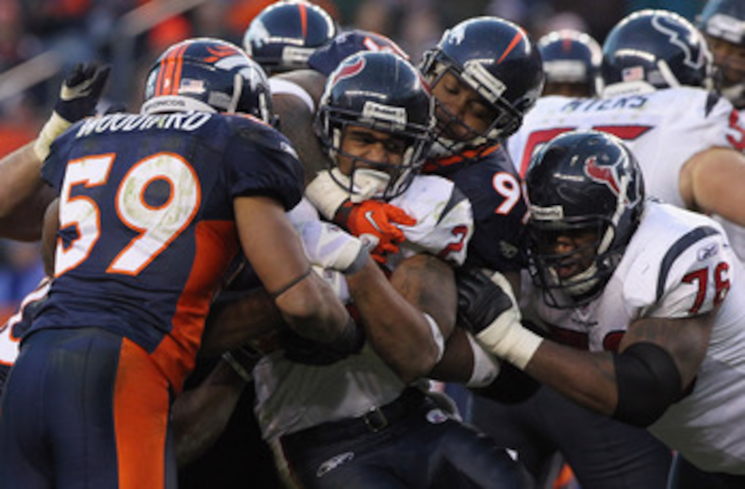 DENVER - DECEMBER 26:  Running back Arian Foster #23 of the Houston Texas is stopped by Kevin Vickerson #99 and Wesley Woodyard #59 of the Denver Broncos at INVESCO Field at Mile High on December 26, 2010 in Denver, Colorado. The Broncos defeated the Texa