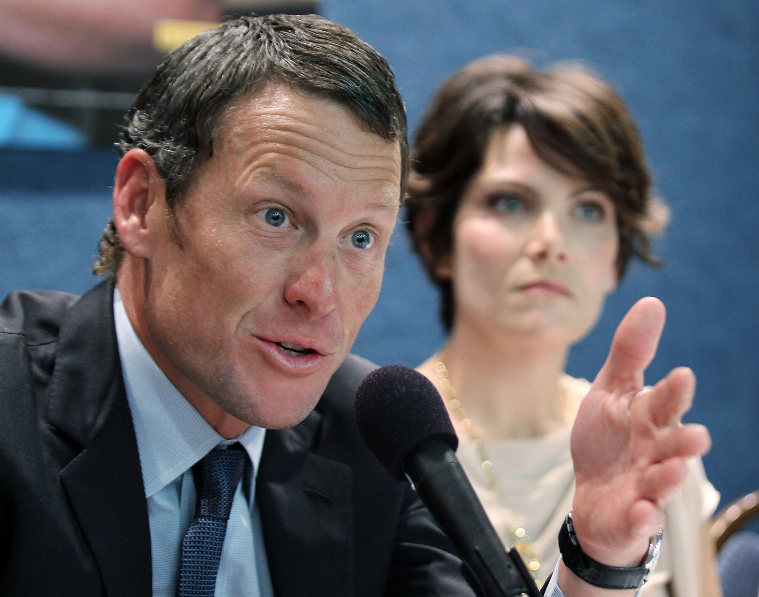 WASHINGTON, DC - MARCH 24:  LIVESTRONG Founder and Chairman and seven-time Tour de France champion Lance Armstrong (L) speaks as cancer survivor Tracy Elliman (R) of Kennett Square, Pennsylvania, listens during a news conference at the National Press Club