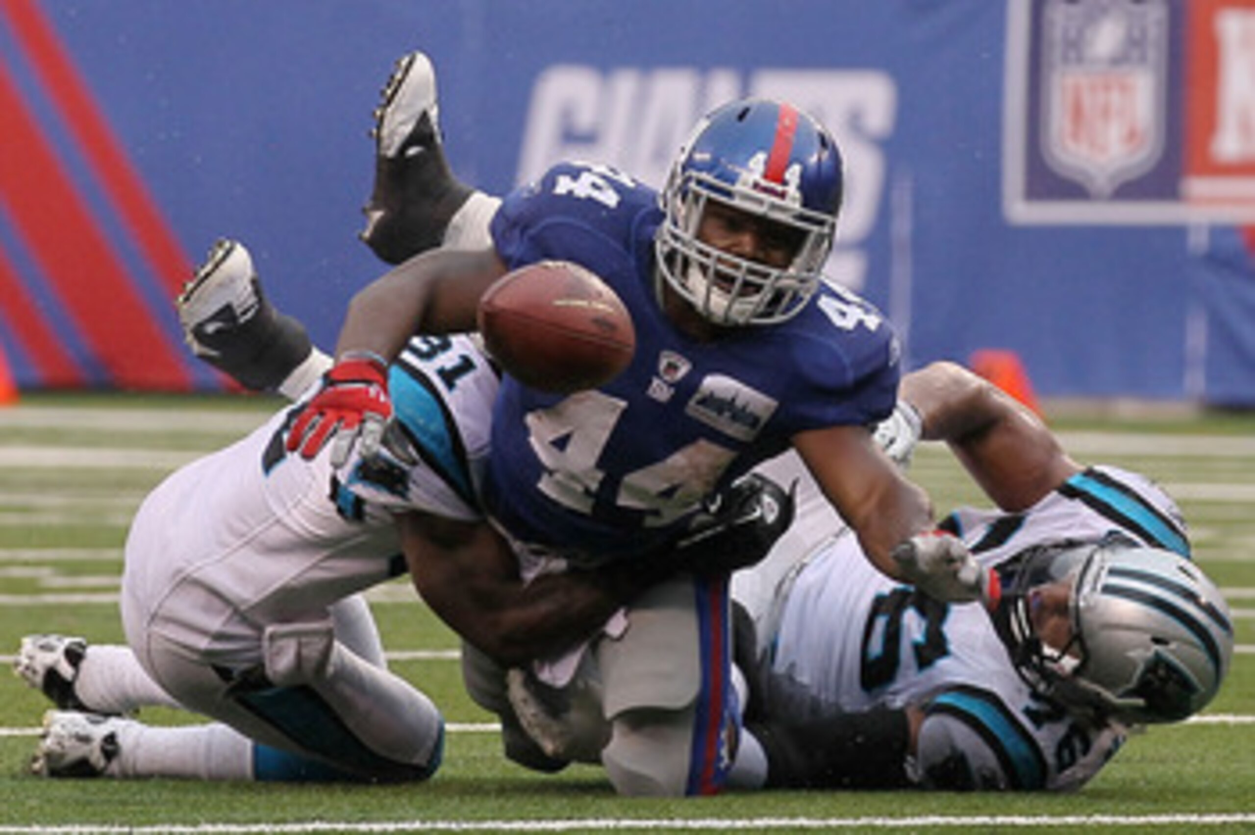 EAST RUTHERFORD, NJ - SEPTEMBER 12:  Ahmad Bradshaw #44 of the New York Giants loses the ball in a tackle by Richard Marshall #31 and Greg Hardy #76 of the Carolina Panthers during the NFL season opener at New Meadowlands Stadium on September 12, 2010 in 