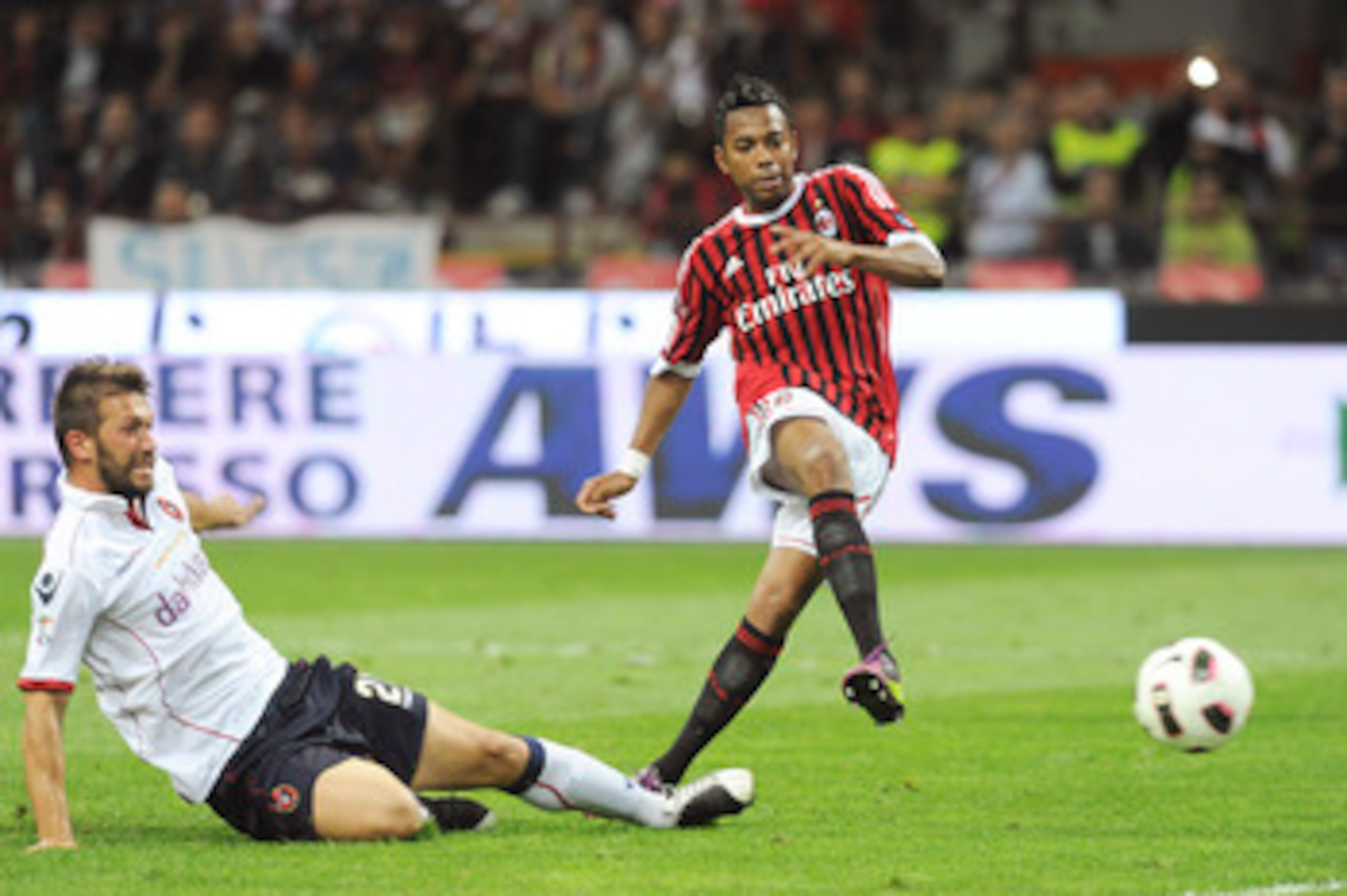 MILAN, ITALY - MAY 14:  Robinho (R) of Milan shoots at goal as he is challenged by Gabriele Perico of Cagliari during the Serie A match between AC Milan and Cagliari Calcio at Stadio Giuseppe Meazza on May 14, 2011 in Milan, Italy.  (Photo by Dino Panato/