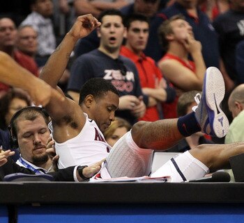 LOS ANGELES, CA - MARCH 12:  Lamont Jones #12 of the Arizona Wildcats falls into the scorer's table in overtime while taking on the Washington Huskies the championship game of the 2011 Pacific Life Pac-10 Men's Basketball Tournament at Staples Center on M