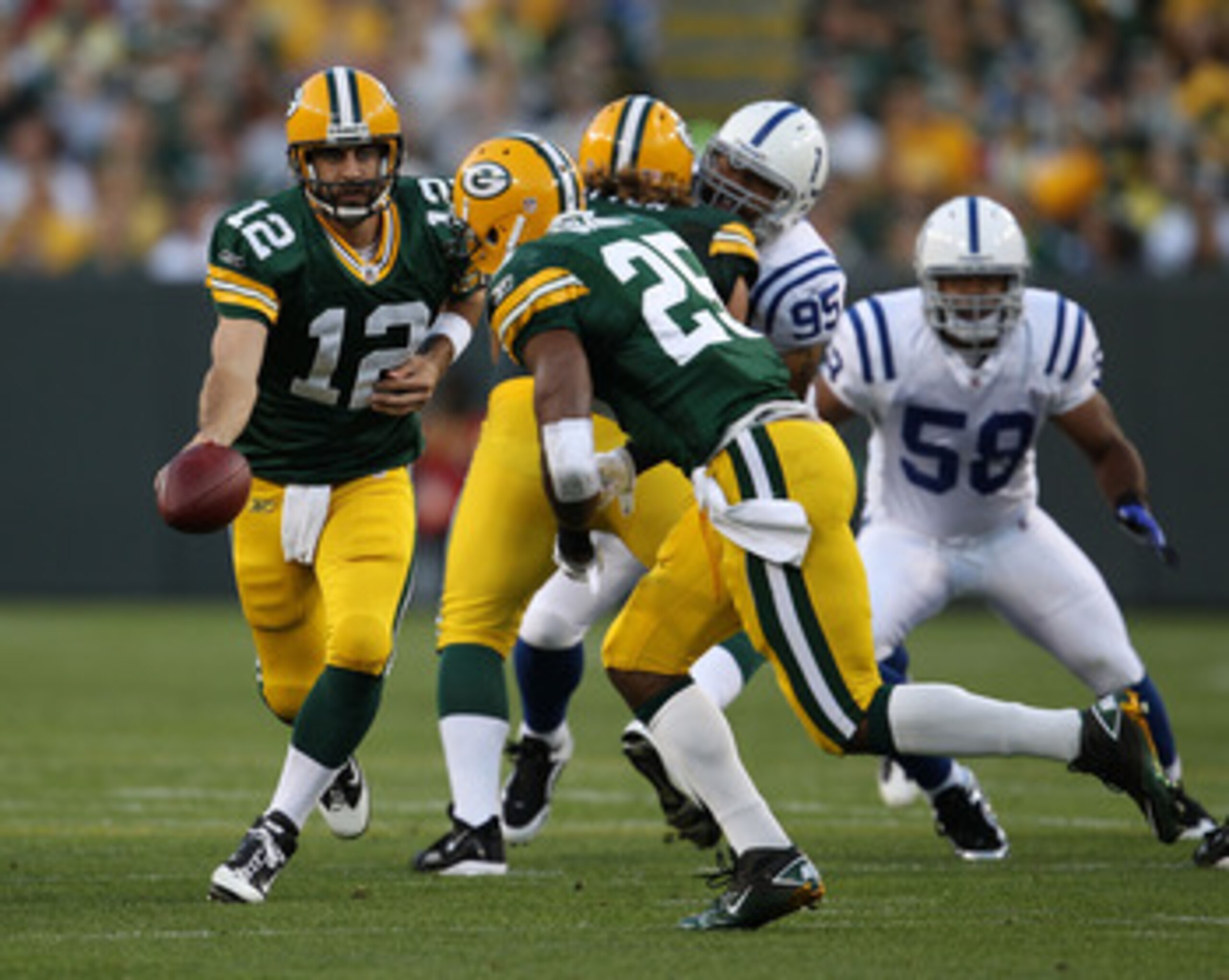 GREEN BAY, WI - AUGUST 26: Aaron Rodgers #12 of the Green Bay Packers turns to hand off to Ryan Grant #25 against the Indianapolis Colts during a preseason game at Lambeau Field on August 26, 2010 in Green Bay, Wisconsin. The Packers defeated the Colts 59