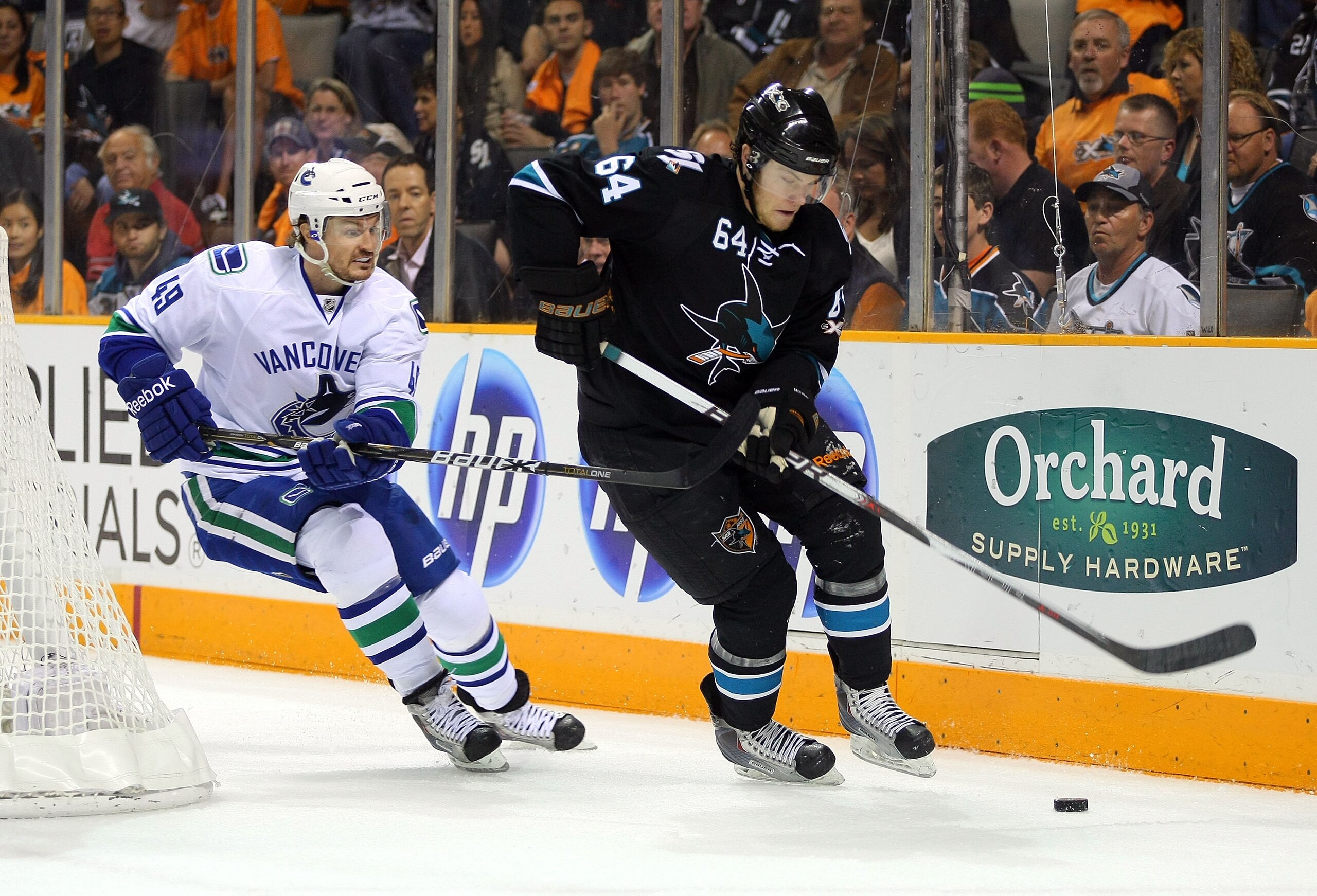 SAN JOSE, CA - MAY 20:  Jamie McGinn #64 of the San Jose Sharks plays the puck around the net under pressure from Alexandre Bolduc #49 of the Vancouver Canucks in Game Three of the Western Conference Finals during the 2011 Stanley Cup Playoffs at HP Pavil
