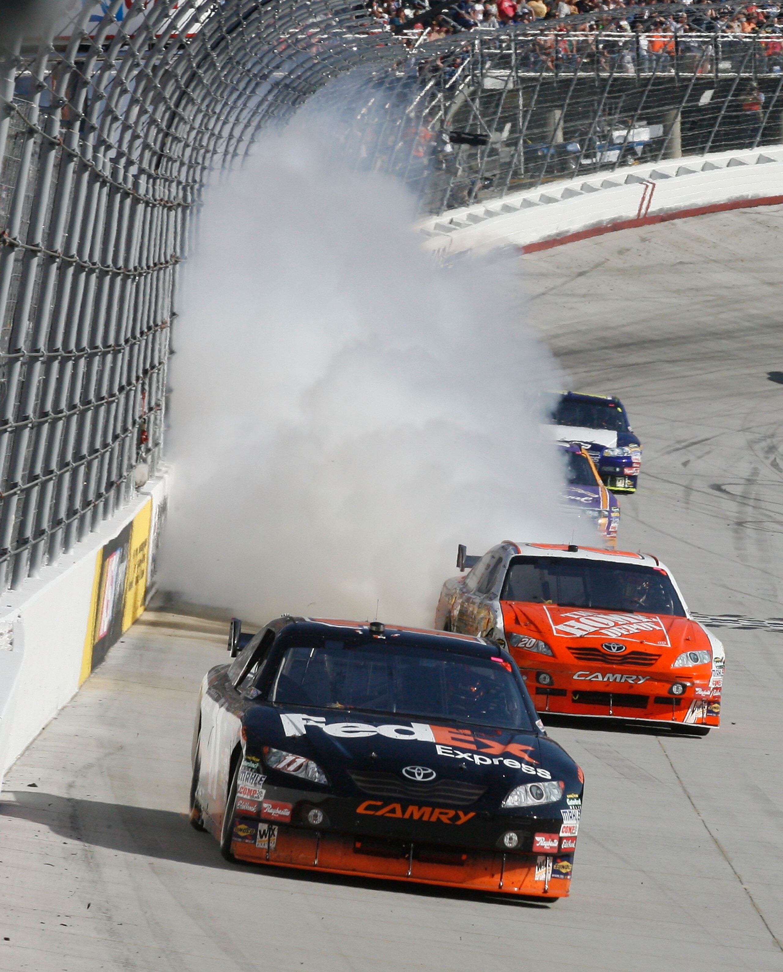 BRISTOL, TN - MARCH 22: Denny Hamlin, driver of the #11 FedEx Express Toyota, passes Joey Logano, driver of the #20 Home Depot Toyota, as Logano's engine blows in the final laps of the NASCAR Sprint Cup Series Food City 500 at Bristol Motor Speedway on Ma