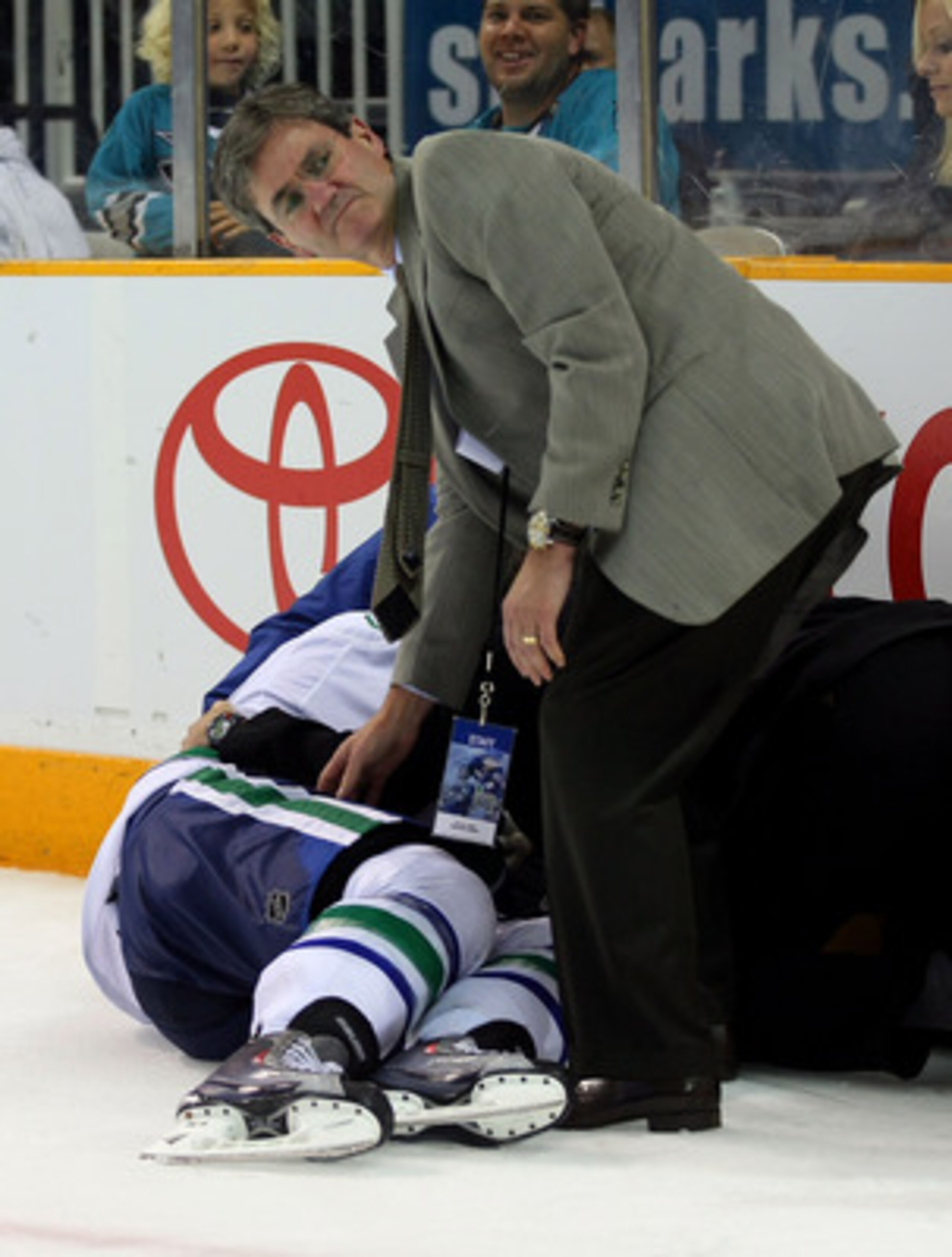 SAN JOSE, CA - MAY 20:  Vancouver Canucks team doctor Bill Regan attends to player Aaron Rome #29 after Rome was checked into the glass by Jamie McGinn #64 of the San Jose Sharks (not in photo) in the third period n Game Three of the Western Conference Fi