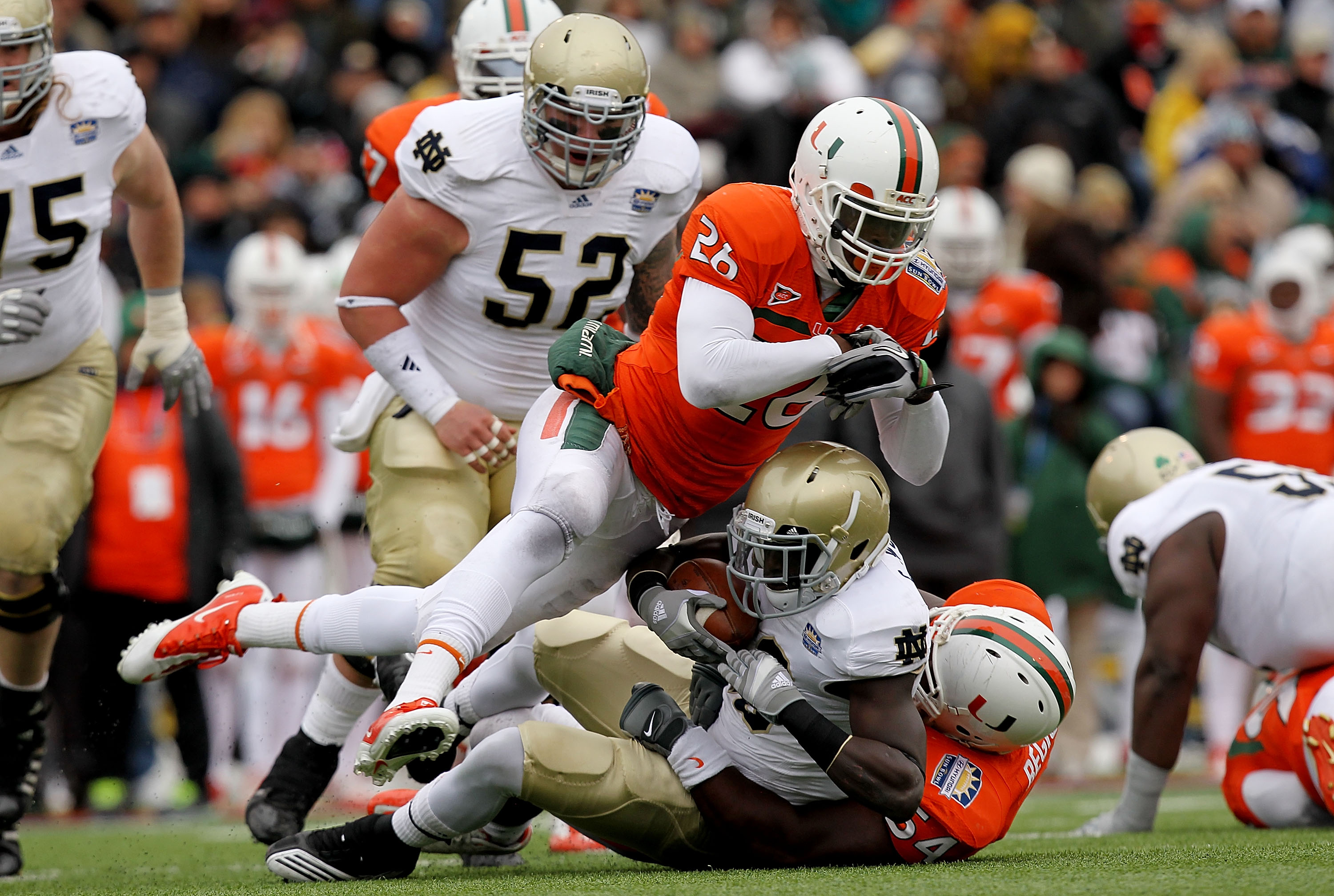 EL PASO, TX - DECEMBER 30:  Running back Cierre Wood #20 of the Notre Dame Fighting Irish is tackled by Ray-Ray Armstrong #26 and Micanor Regis #54 of the Miami Hurricanes at Sun Bowl on December 30, 2010 in El Paso, Texas.  (Photo by Ronald Martinez/Gett