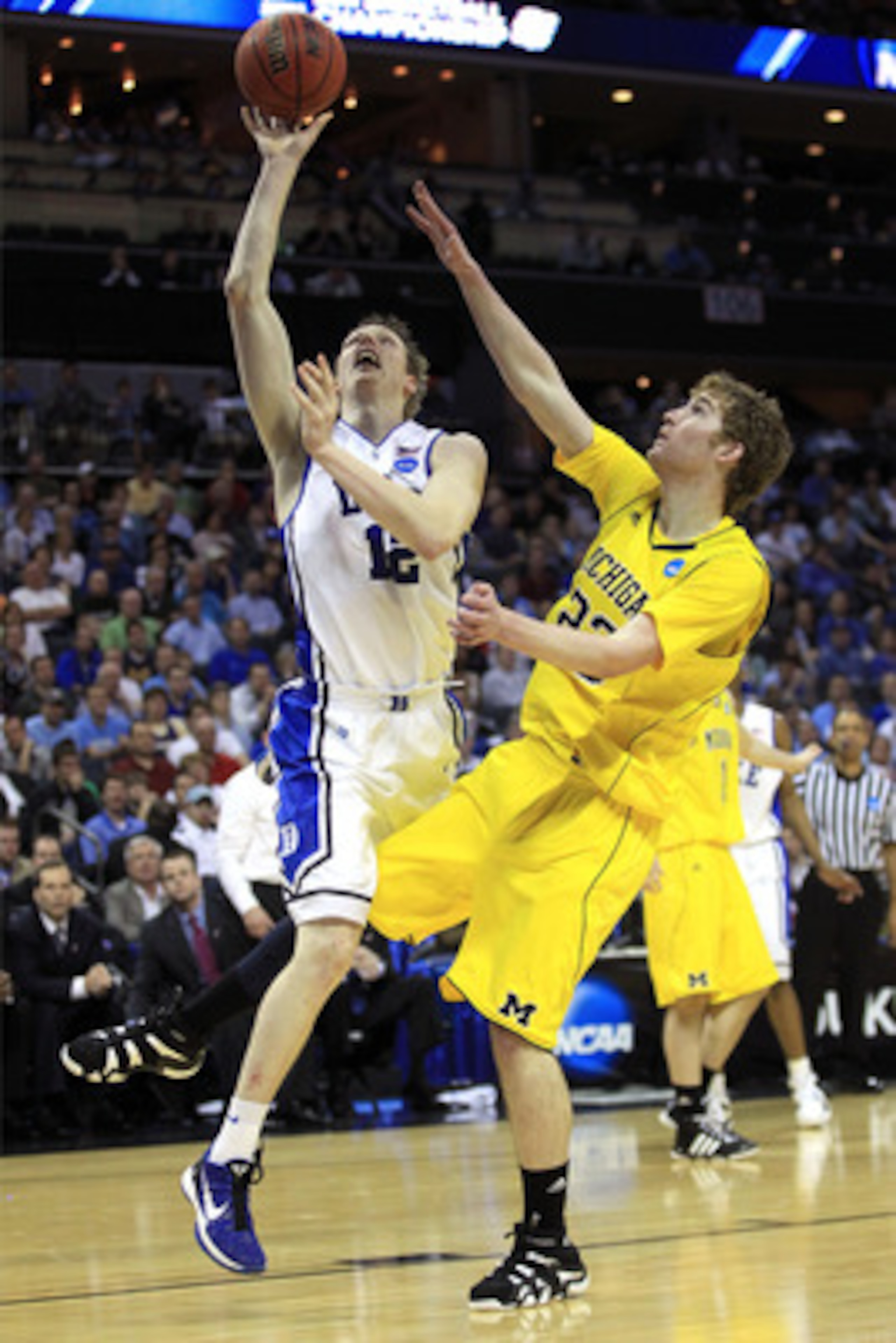 CHARLOTTE, NC - MARCH 20:  Kyle Singler #12 of the Duke Blue Devils goes up for a shot over Evan Smotrycz #23 of the Michigan Wolverines in the second half during the third round of the 2011 NCAA men's basketball tournament at Time Warner Cable Arena on M
