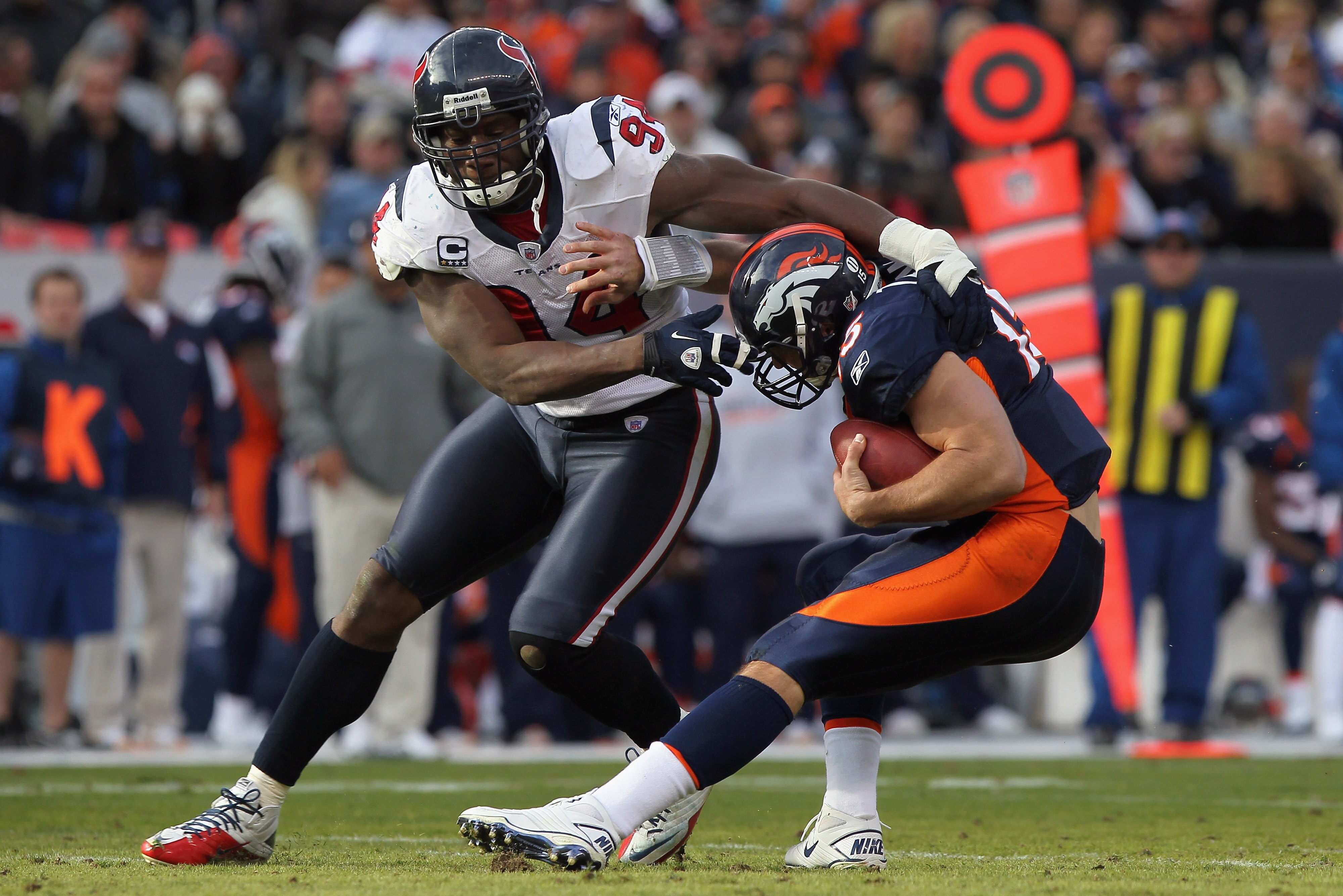 DENVER - DECEMBER 26:  Quarterback Tim Tebow #15 of the Denver Broncos eludes a sack attempt by defensive end Antonio Smith #94 of the Houston Texas at INVESCO Field at Mile High on December 26, 2010 in Denver, Colorado.  (Photo by Doug Pensinger/Getty Im