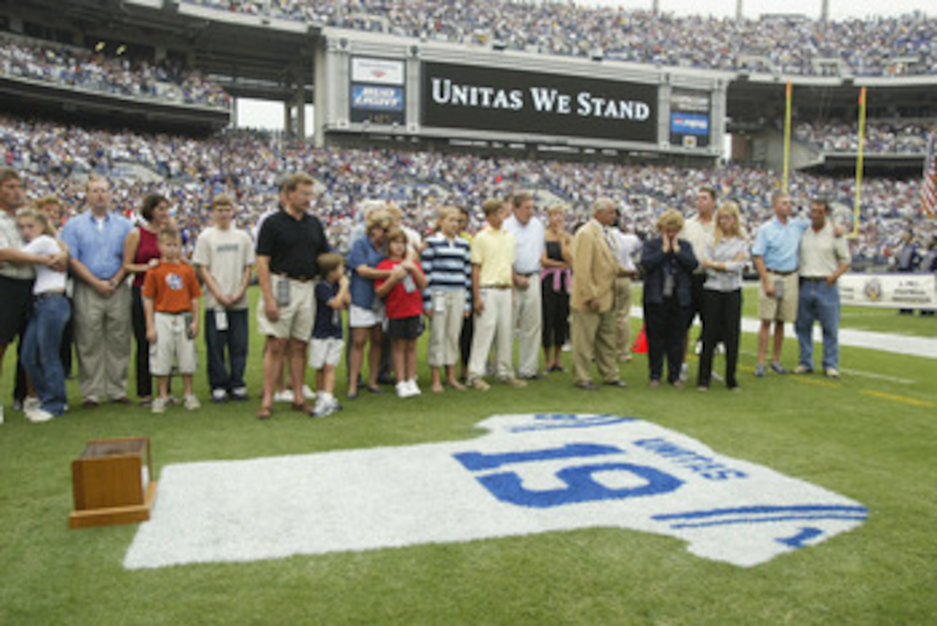 BALTIMORE - SEPTEMBER  15:  Family and friends pay tribute to Johnny Unitas as they stand behind a jersey painted with his name and uniform number on the grass prior to the game between the Tampa Bay Buccaneers and the Baltimore Ravens on September 15, 20