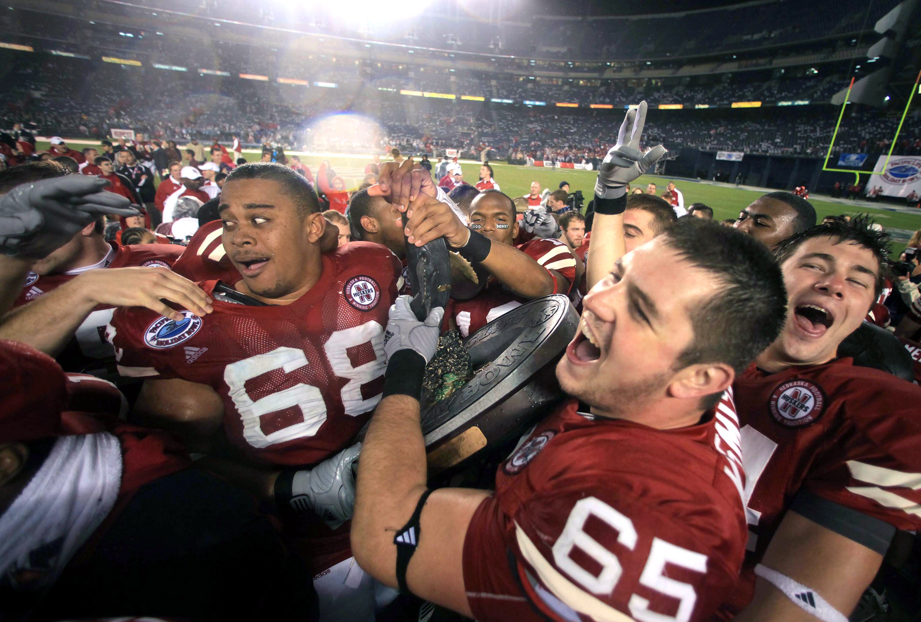 SAN DIEGO, CA - DECEMBER 30:  Keith Williams #68, Mike Smith #65, and Mike McNeill #44 of the University of Nebraska Cornhuskers hoist the bowl trophy after defeating the University of Arizona Wildcats during the Pacific Life Holiday Bowl, on December 30,