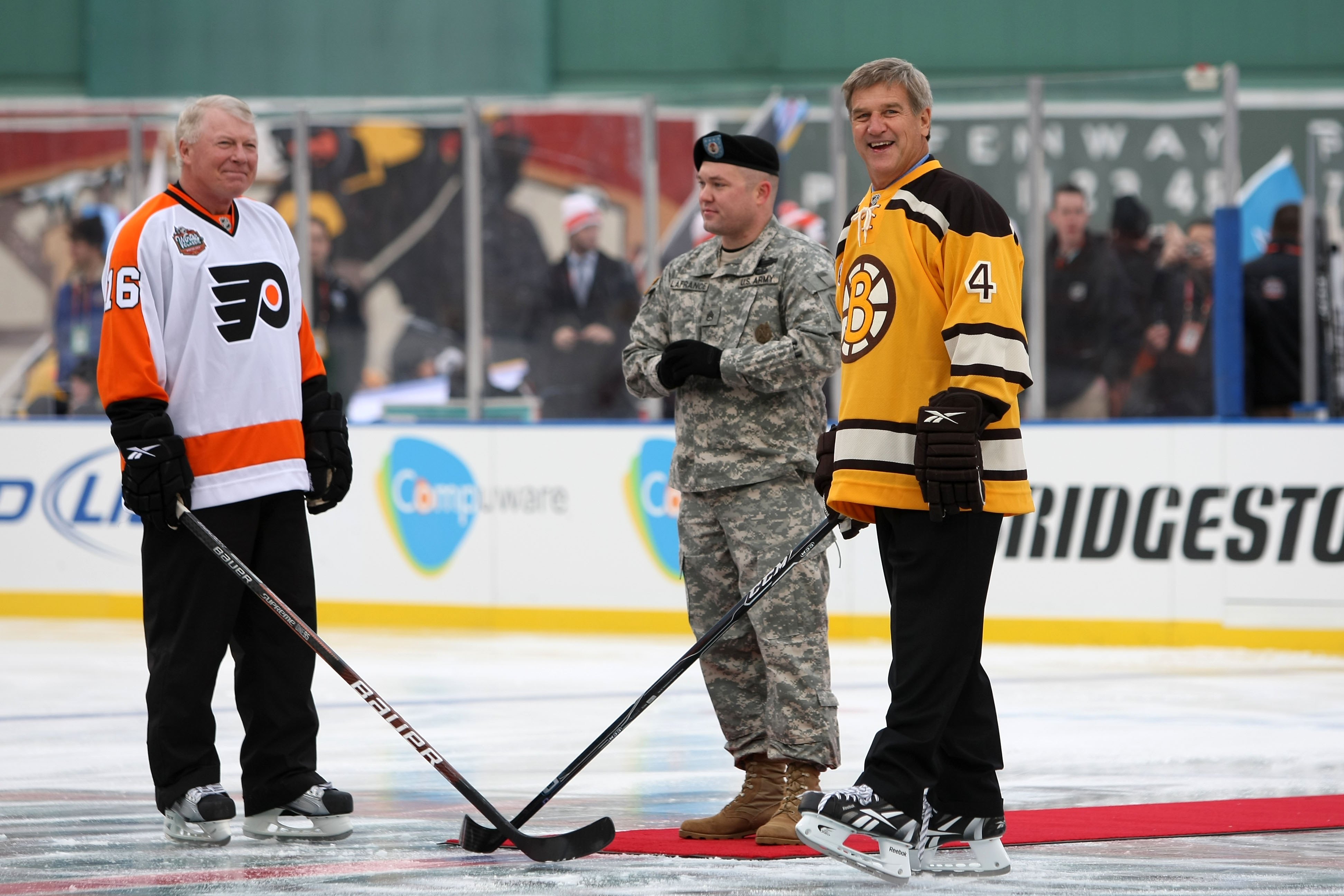 BOSTON - JANUARY 01:  Staff Sergeant Ryan R. LaFrance (C) prepares to drop the ceremonial first puck for Bobby Clarke #16 (L) honorary captain of the Philadelphia Flyers and Bobby Orr #4 (R) honorary captain of the Boston Bruins during the 2010 Bridgeston