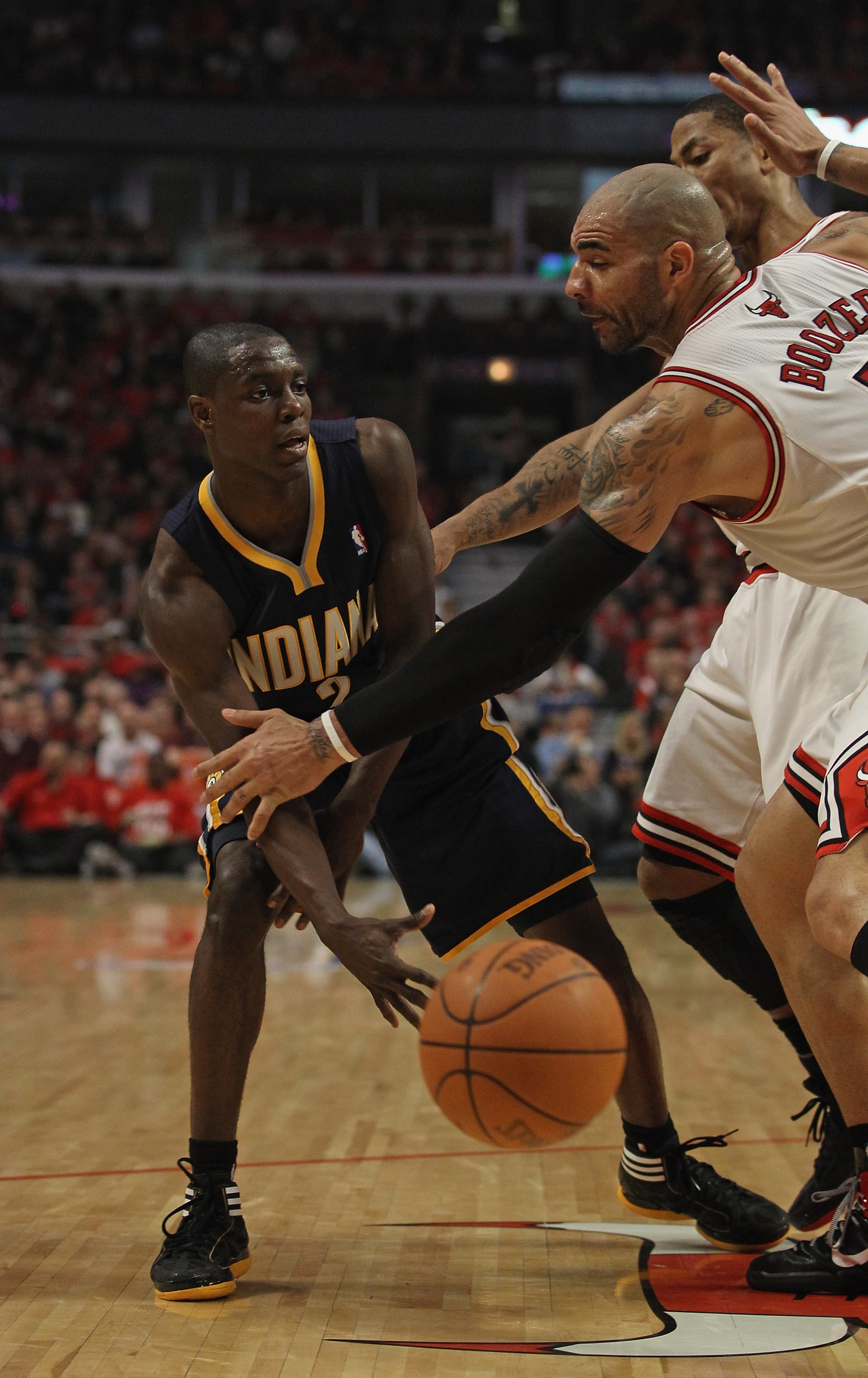 CHICAGO, IL - APRIL 16: Darren Collison #2 of the Indiana Pacers passes the ball against Carlos Boozer #5 and Derrick Rose #1 of the Chicago Bulls in Game One of the Eastern Conference Quarterfinals in the 2011 NBA Playoffs at the United Center on April 1