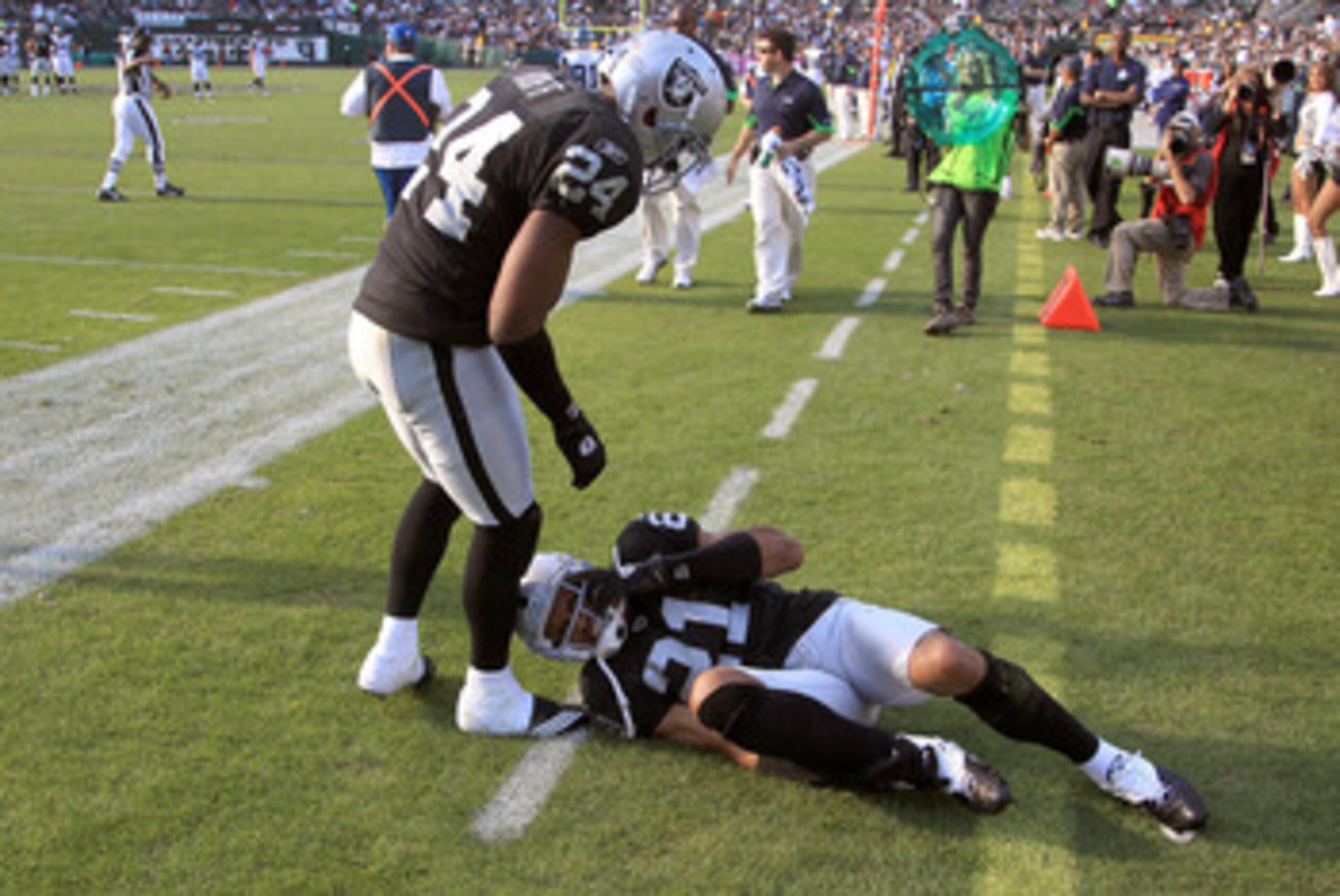 OAKLAND, CA - OCTOBER 31:  Michael Huff #24 checks on injured teammate Nnamdi Asomugha #21 of the Oakland Raiders during their game against the Seattle Seahawks at Oakland-Alameda County Coliseum on October 31, 2010 in Oakland, California.  (Photo by Ezra
