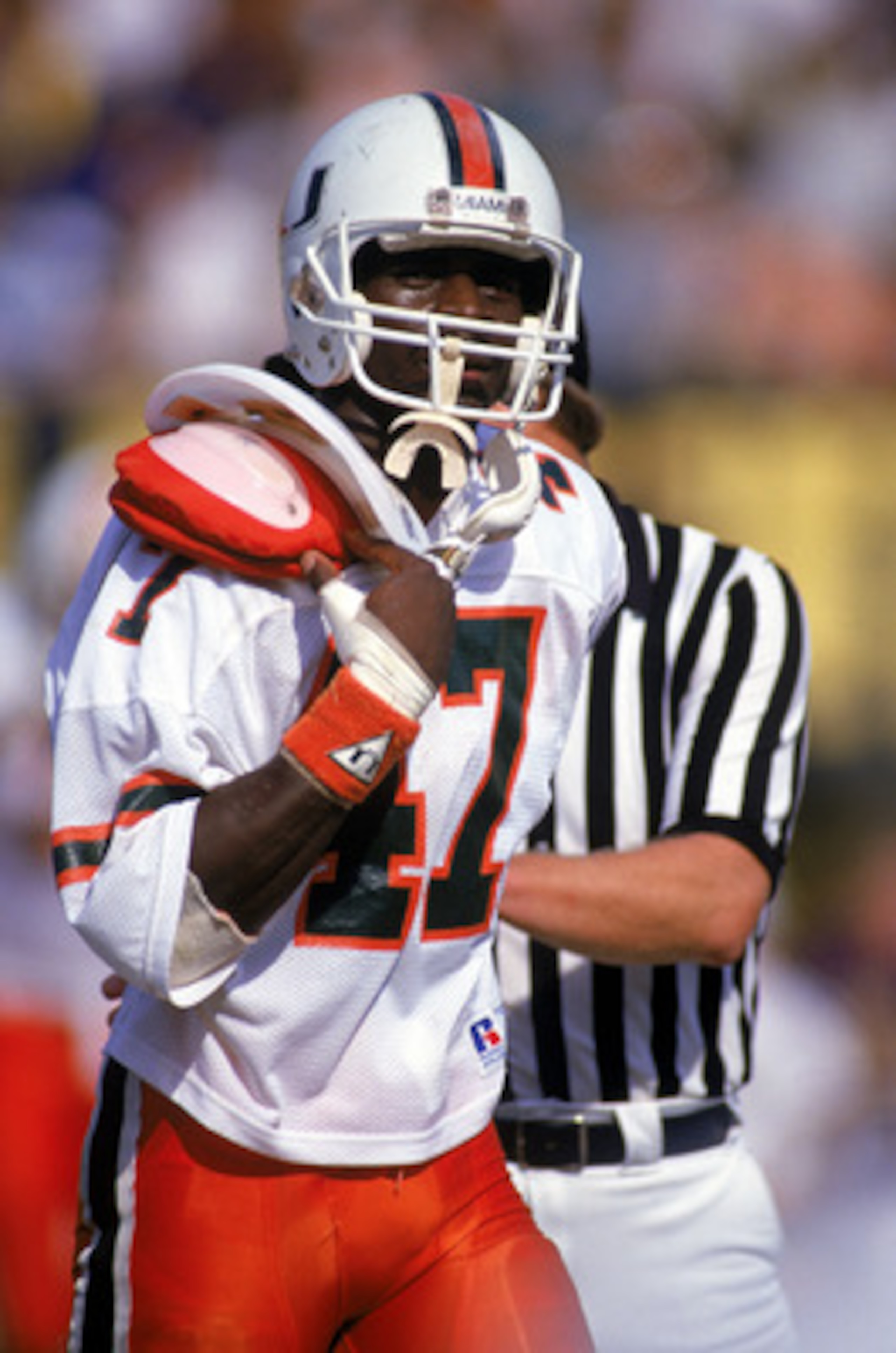 1987:  Wide receiver Michael Irving #47 of the University of Miami Hurricanes runs on the field as he tries to adjust his uniform over his shoulder pads during a 1987 NCAA game. (Photo by Allen Steele/Getty Images)
