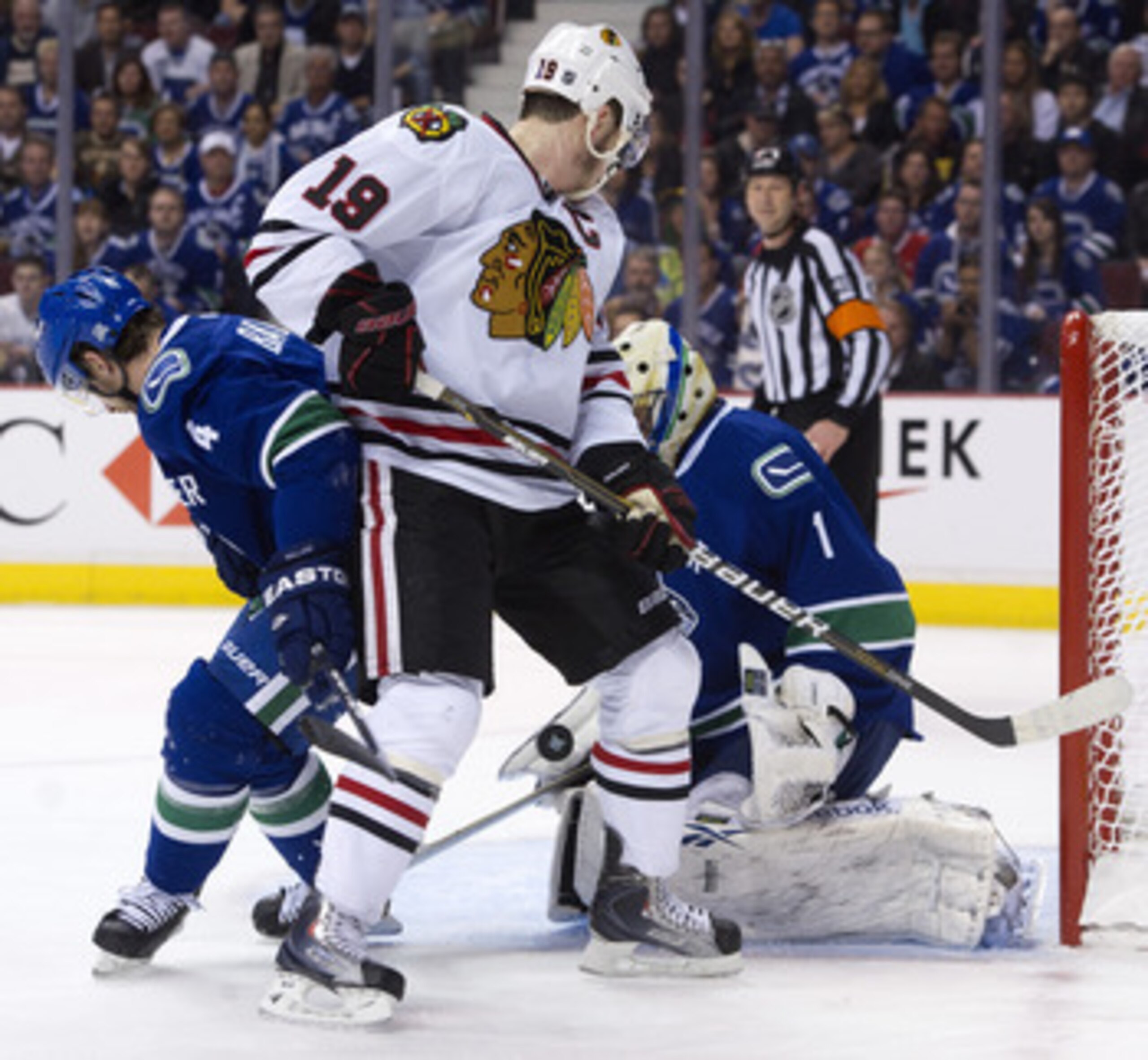VANCOUVER, CANADA - APRIL 26: Goalie Roberto Luongo #1 of the Vancouver Canucks makes a save while Jonathan Toews #19 of the Chicago Blackhawks and Keith Ballard #4 of the Vancouver Canucks  battle for position in front of the net during the first period