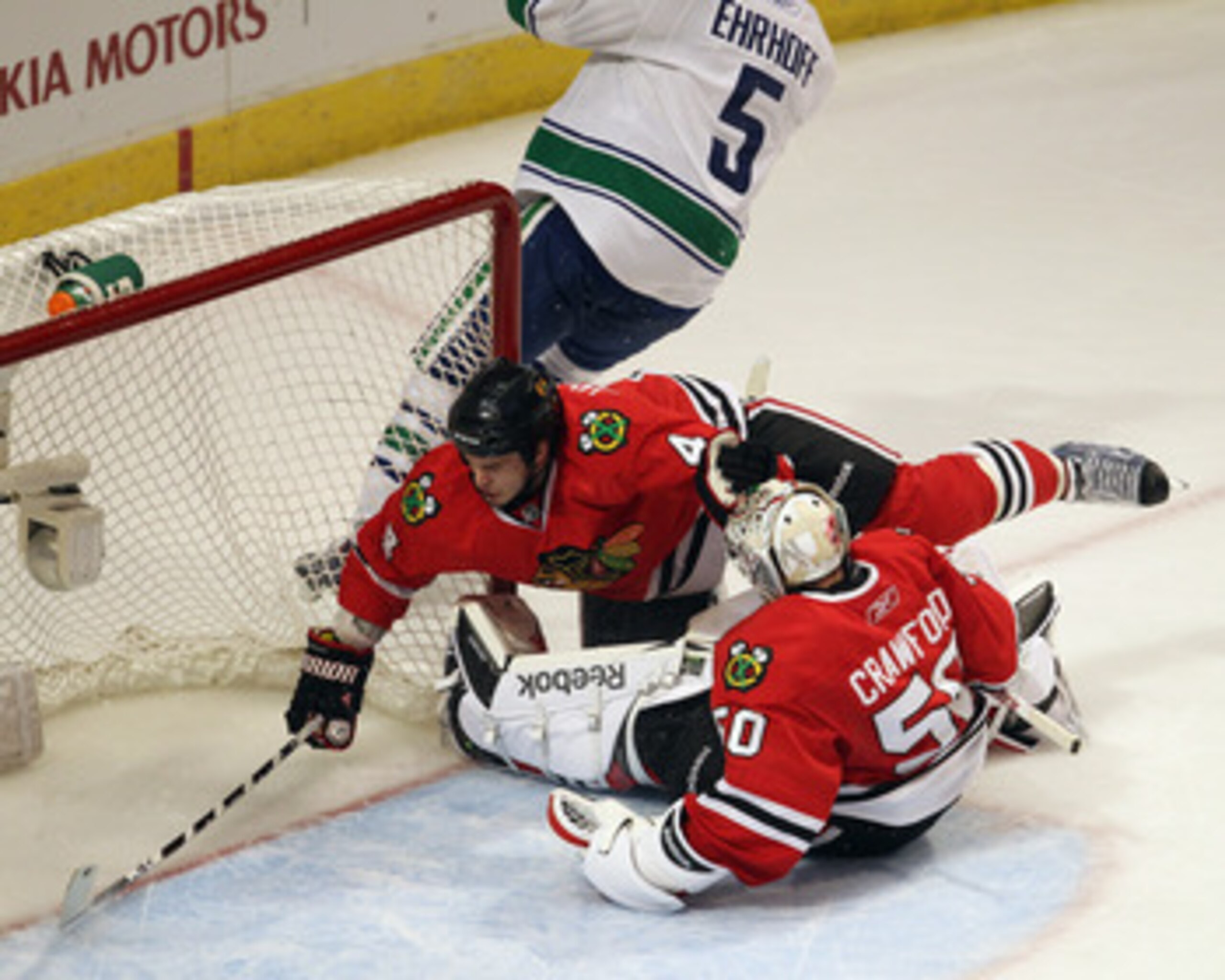 CHICAGO, IL - APRIL 19: Niklas Hjalmarsson #4 of the Chicago Blackhawks is pushed over teammate Corey Crawford #50 by Christian Ehrhoff #5 of the Vancouver Canucks in Game Four of the Western Conference Quarterfinals during the 2011 NHL Stanley Cup Playof
