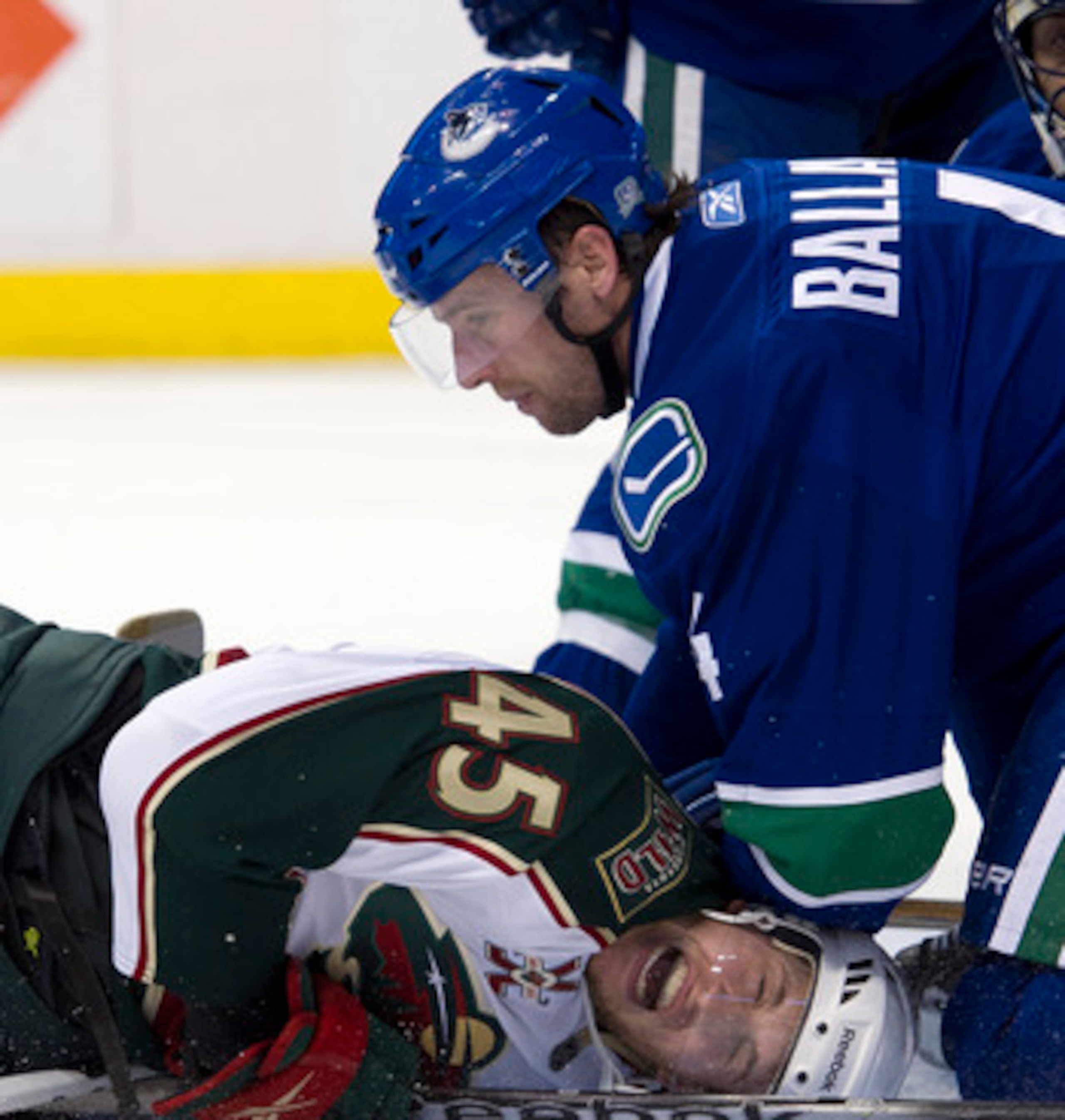 VANCOUVER, CANADA - APRIL 7: Carson McMillan #45 of the Minnesota Wild reacts as he pinned down on the ice by Keith Ballard #4 of the Vancouver Canucks during the third period in NHL action on April 07, 2011 at Rogers Arena in Vancouver, BC, Canada.  (Pho