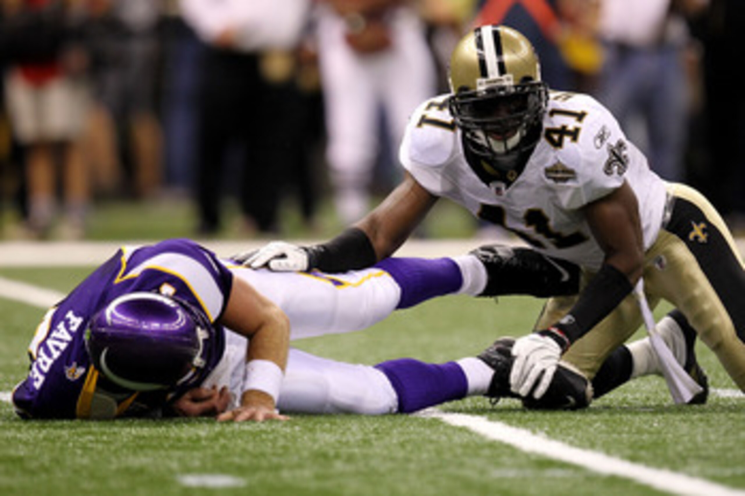 NEW ORLEANS - SEPTEMBER 09:  Quarterback Brett Favre #4 of the Minnesota Vikings lies on the turf after taking a hard hit from Roman Harper #41 of the New Orleans Saints at Louisiana Superdome on September 9, 2010 in New Orleans, Louisiana.  (Photo by Ron