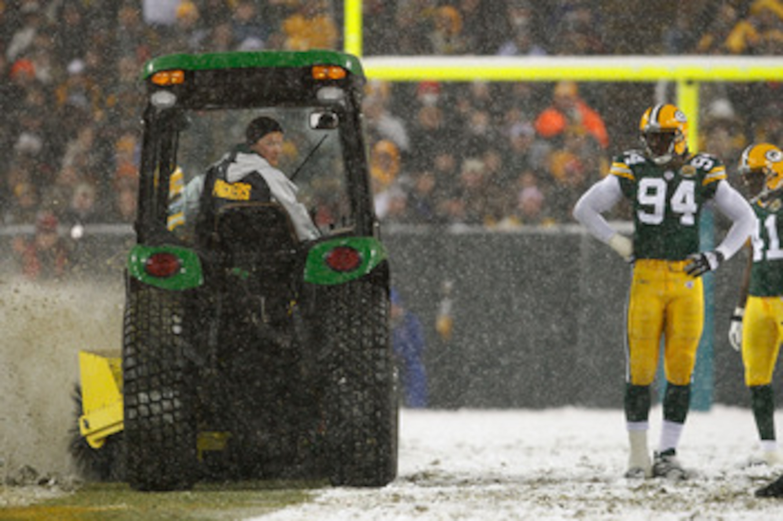 GREEN BAY, WI - JANUARY 12:  Defensive end Kabeer Gbaja-Biamila #94 of the Green Bay Packers watches as a snow plow drives down the middle of the field in the fourth quarter of the game against the Seattle Seahawks during the NFC divisional playoff game o