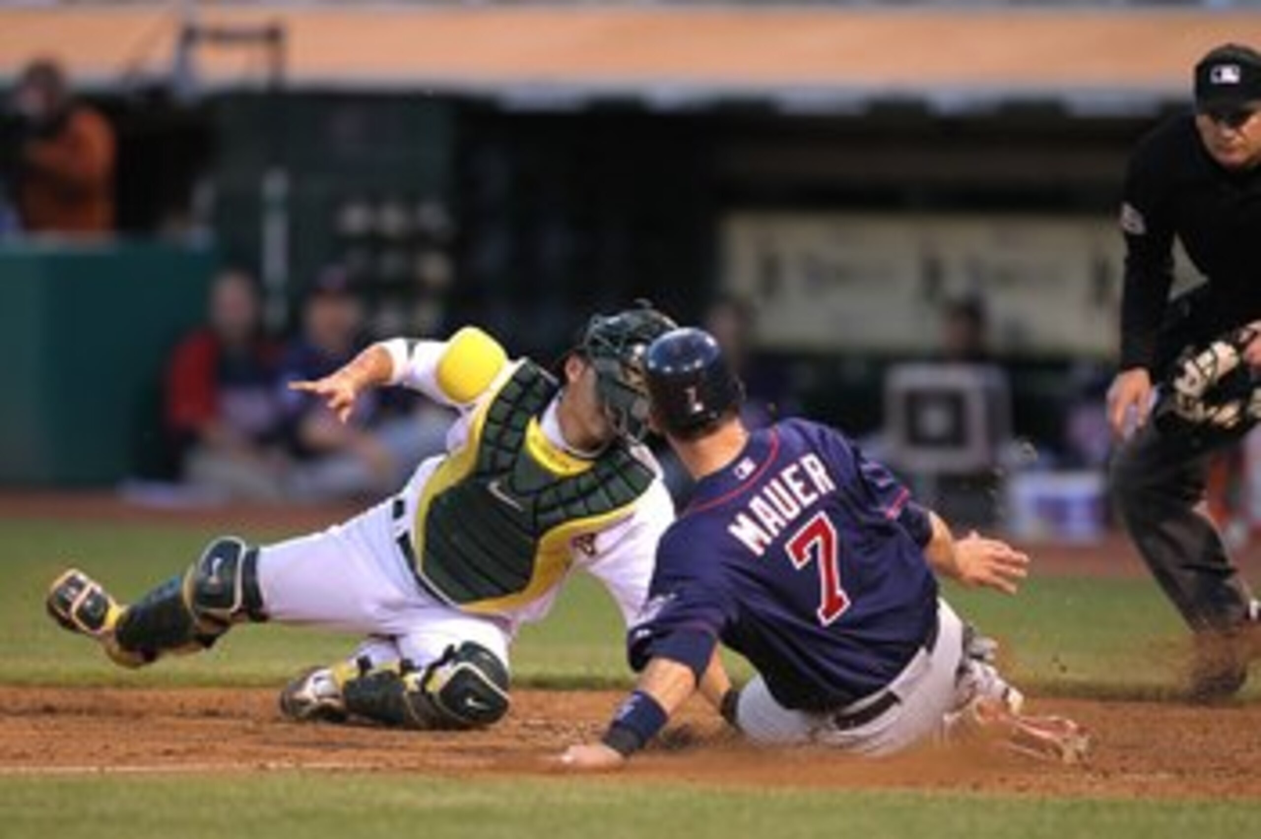 OAKLAND, CA - JUNE 04:  Joe Mauer #7 of the Minnesota Twins scores past Kurt Suzuki #8 of the Oakland Athletics on a single hit by Jason Kubel in the sixth inning during an MLB game at the Oakland-Alameda County Coliseum on June 4, 2010 in Oakland, Califo