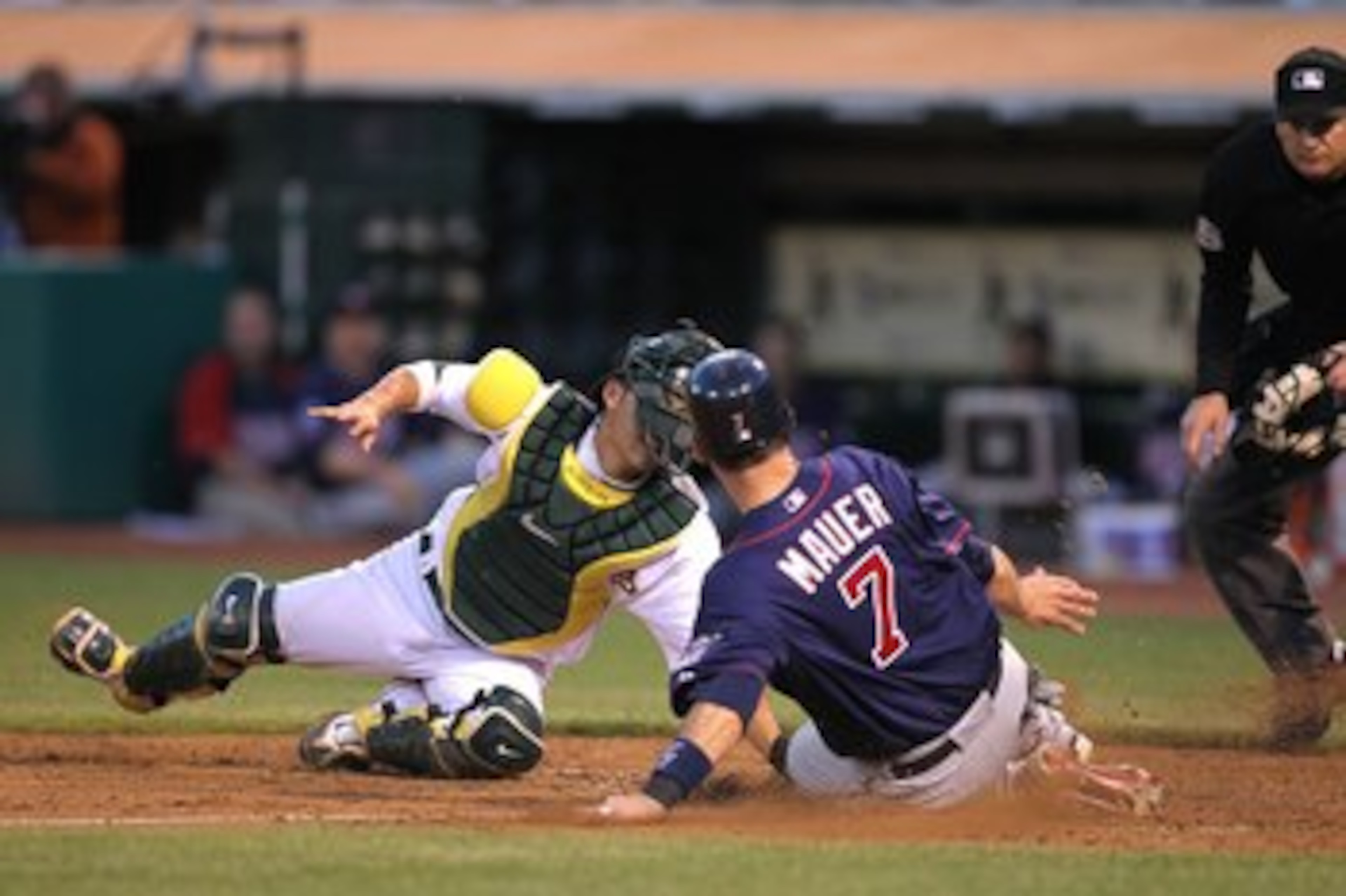 OAKLAND, CA - JUNE 04:  Joe Mauer #7 of the Minnesota Twins scores past Kurt Suzuki #8 of the Oakland Athletics on a single hit by Jason Kubel in the sixth inning during an MLB game at the Oakland-Alameda County Coliseum on June 4, 2010 in Oakland, Califo