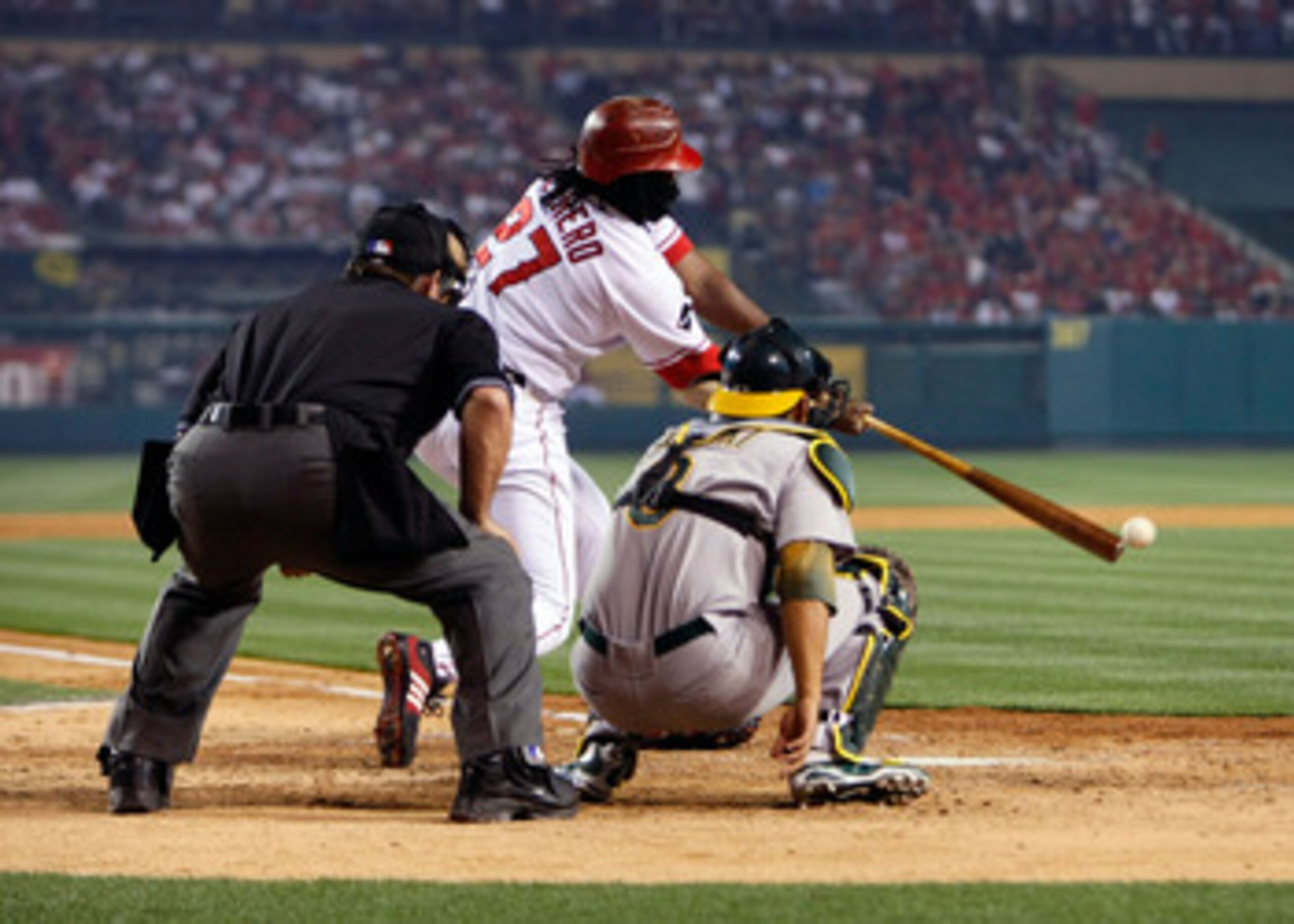ANAHEIM, CA - APRIL 06:  Vladimir Guerrero #27 of the Los Angeles Angels of Anaheim hits a single in the fifth inning as home plate umpire Charlie Reliford and Oakland Athletics catcher Kurt Suzuki #8 look on, on Opening Day at Angel Stadium on April 6, 2