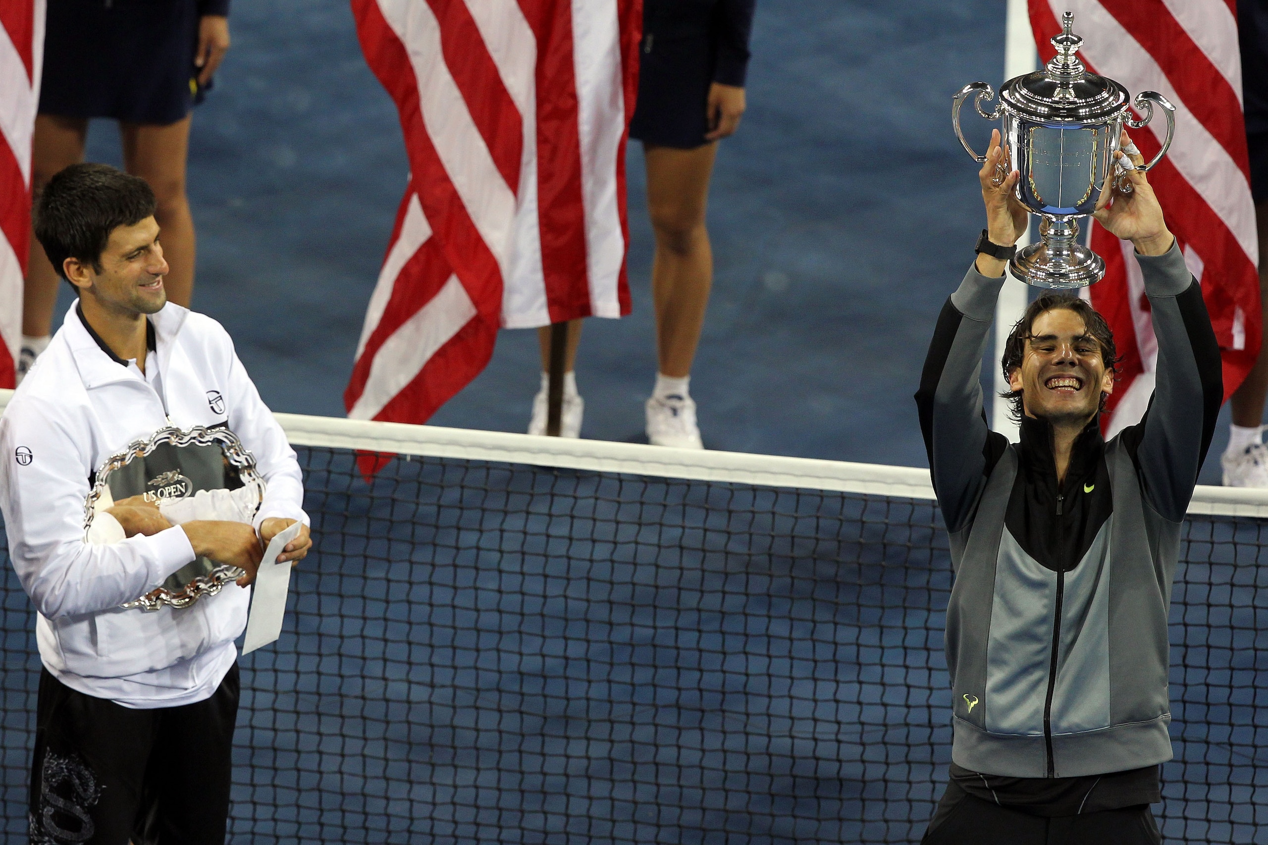 NEW YORK - SEPTEMBER 13:  Rafael Nadal of Spain (R) celebrates with the championship trophy as runner up Novak Djokovic of Serbia (L) looks on after their men's singles final on day fifteen of the 2010 U.S. Open at the USTA Billie Jean King National Tenni