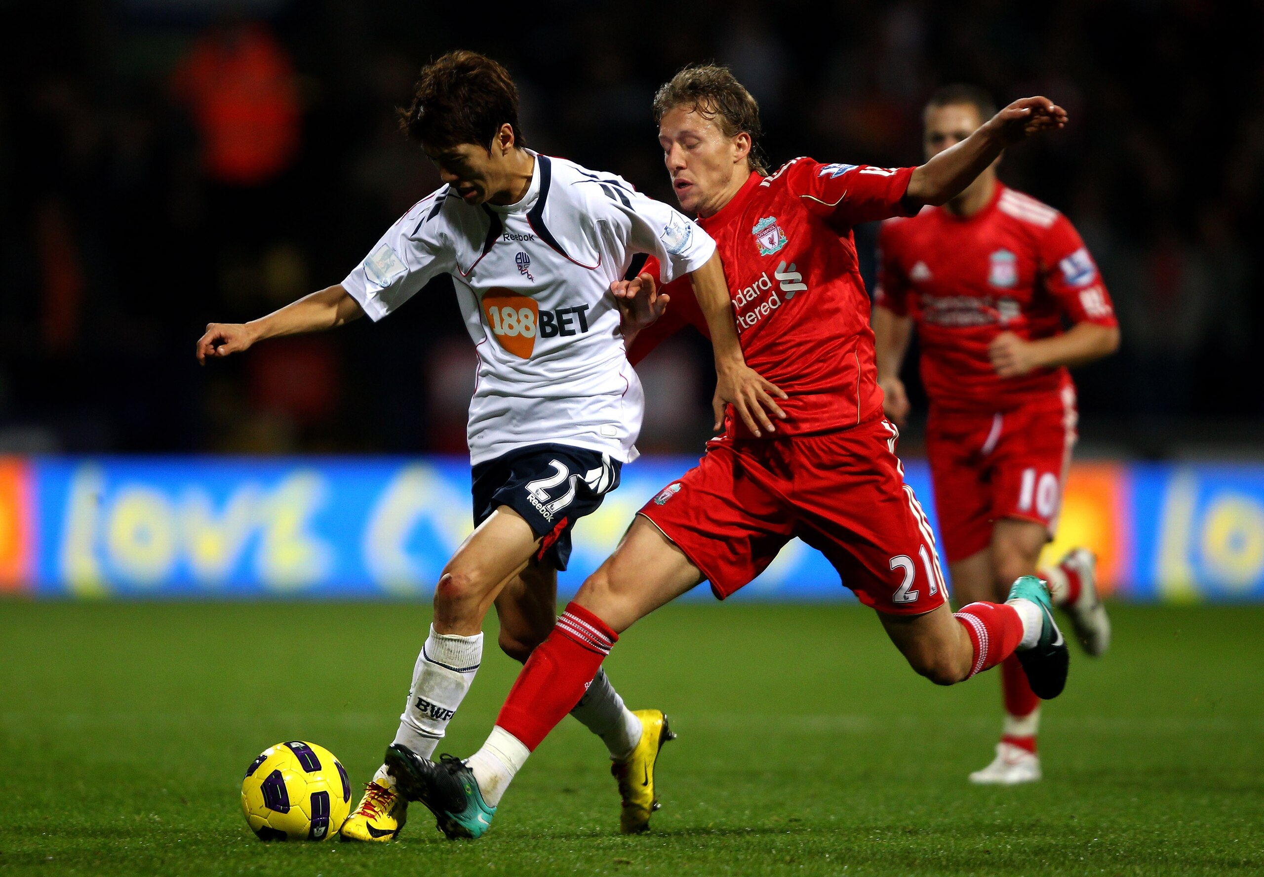 BOLTON, ENGLAND - OCTOBER 31:  Lucas of Liverpool tussles for posession with Chung Yong Lee of Bolton Wanderers during the Barclays Premier League match between Bolton Wanderers and Liverpool at the Reebok Stadium on October 31, 2010 in Bolton, England.