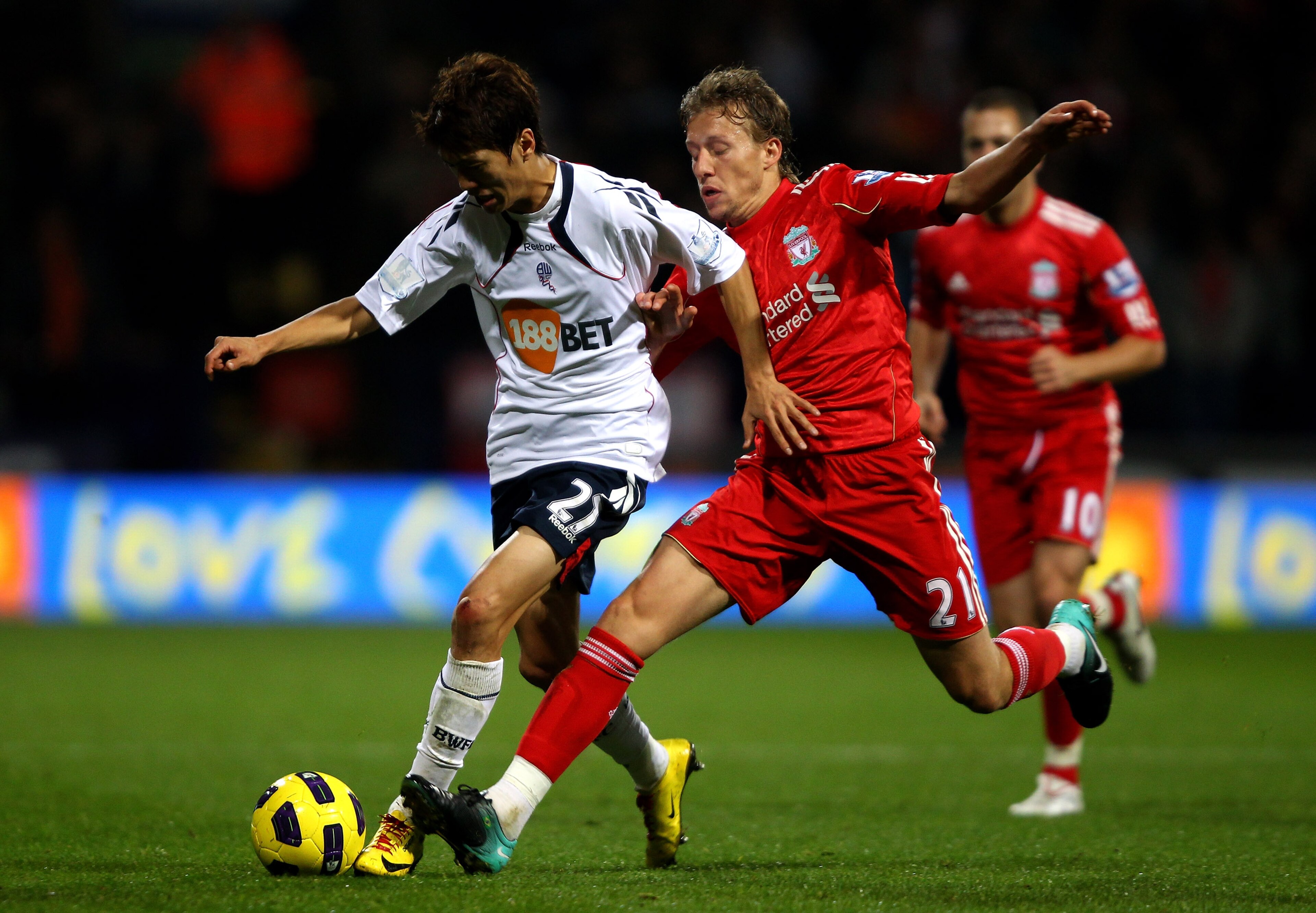 BOLTON, ENGLAND - OCTOBER 31:  Lucas of Liverpool tussles for posession with Chung Yong Lee of Bolton Wanderers during the Barclays Premier League match between Bolton Wanderers and Liverpool at the Reebok Stadium on October 31, 2010 in Bolton, England.