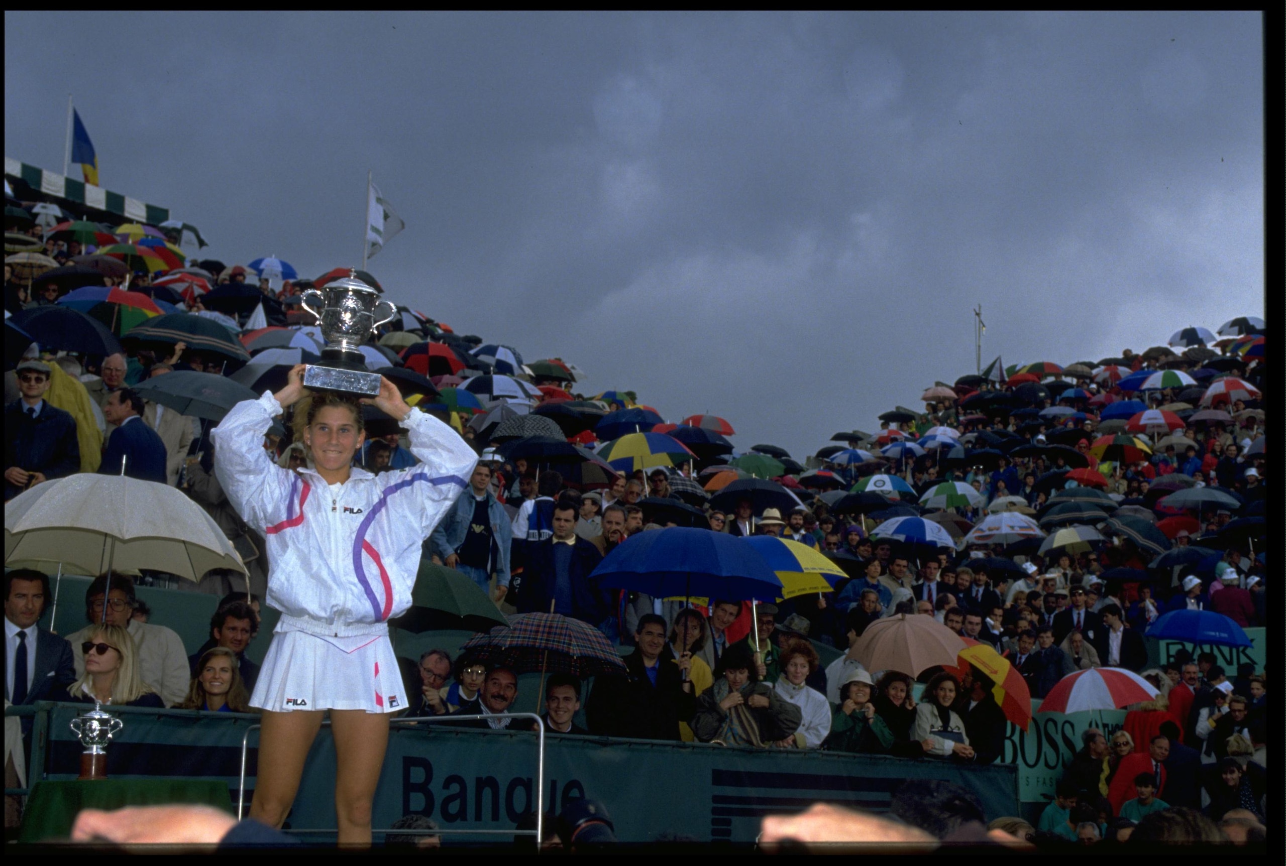 9 JUN 1990:  MONICA SELES OF YUGOSLAVIA SHIELDS HERSELF FROM THE RAIN WITH THE TROPHY AFTER DEFEATING STEFFI GRAF OF GERMANY IN THE FINAL OF THE 1990 FRENCH OPEN PLAYED AT ROLAND GARROS. SELES WON THE MATCH 7-6 (8-6) AND 6-4.