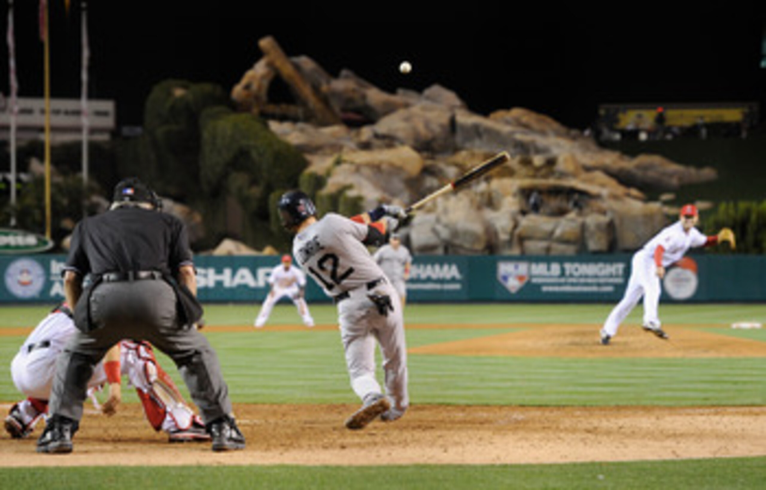 ANAHEIM, CA - APRIL 21:  Jed Lowrie #12 of the Boston Red Sox hits a sacrifice fly ball by to score teammate Dustin Pedroia #15 from third base in the 11th inning of the baseball game against Los Angeles Angels of Anaheim at Angel Stadium of Anaheim on Ap