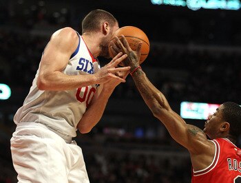 CHICAGO, IL - MARCH 28: Derrick Rose #1 of the Chicago Bulls reaches for the ball going off of the face of Spencer Hawes #00 of the Philadelphia 76ers at the United Center on March 28, 2011 in Chicago, Illinois. NOTE TO USER: User expressly acknowledges a