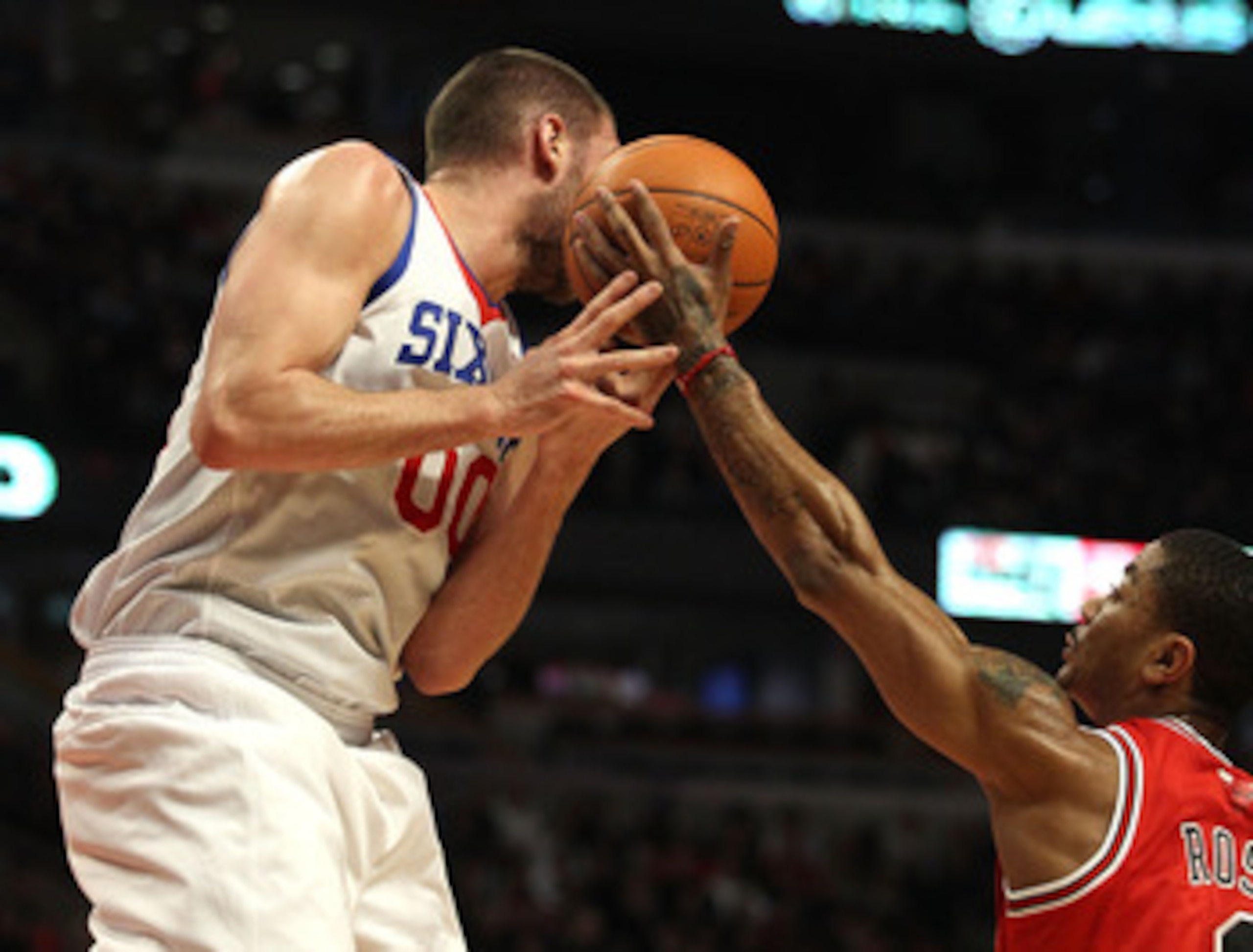 CHICAGO, IL - MARCH 28: Derrick Rose #1 of the Chicago Bulls reaches for the ball going off of the face of Spencer Hawes #00 of the Philadelphia 76ers at the United Center on March 28, 2011 in Chicago, Illinois. NOTE TO USER: User expressly acknowledges a