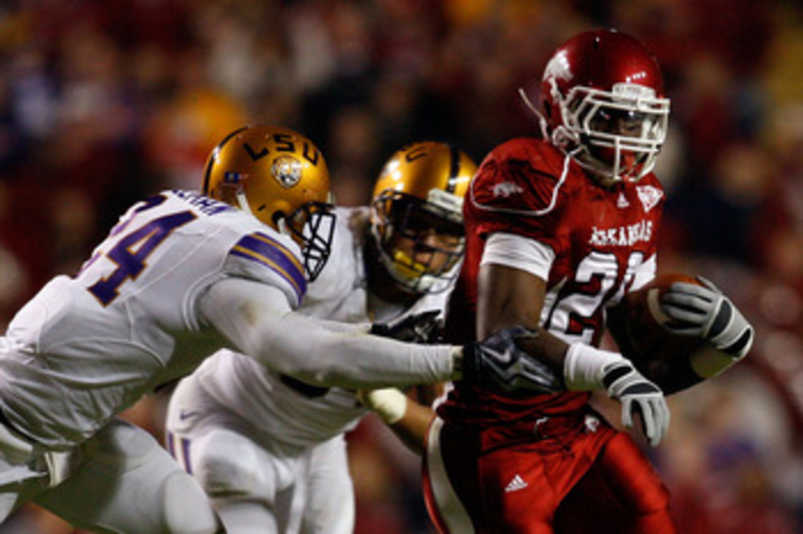 BATON ROUGE, LA - NOVEMBER 28:  Ronnie Wingo Jr. #20 of the Arkansas Razorbacks avoids a tackle by Harry Coleman #24 and Rahim Alem #84 of the LSU Tigers at Tiger Stadium on November 28, 2009 in Baton Rouge, Louisiana.  The Tigers defeated the Razorbacks 