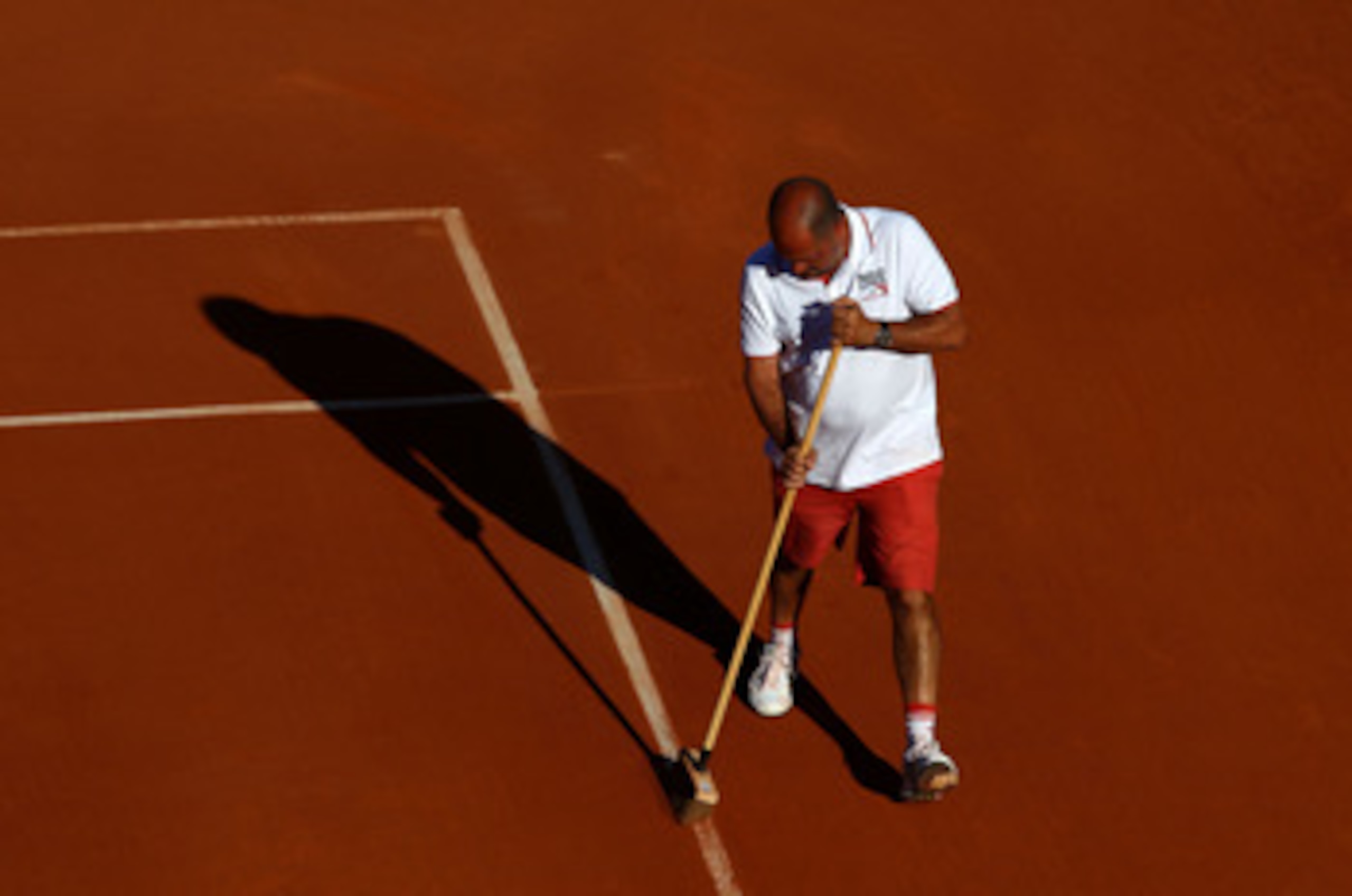 PARIS, FRANCE - MAY 25:  A member of the ground staff sweeps clay dust from the court lines during a break in the women's singles round two match between Vesna Dolonts of Russia and Francesca Schiavone of Italy on day four of the French Open at Roland Gar