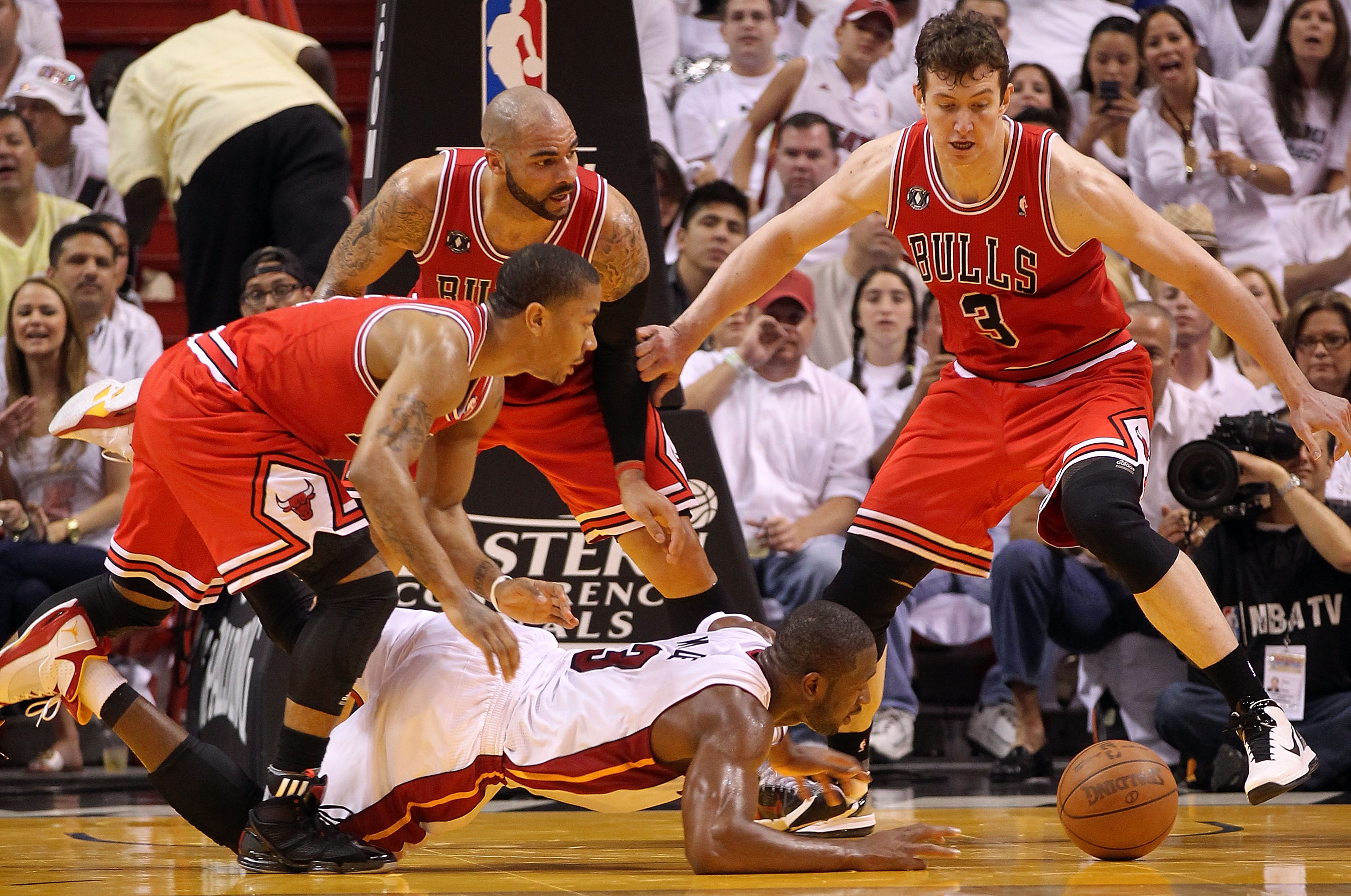 MIAMI, FL - MAY 22:  Dwyane Wade #3 of the Miami Heat dives for a loose ball against Derrick Rose #1, Carlos Boozer #5 and Omer Asik #3 of the Chicago Bulls in Game Three of the Eastern Conference Finals during the 2011 NBA Playoffs on May 22, 2011 at Ame
