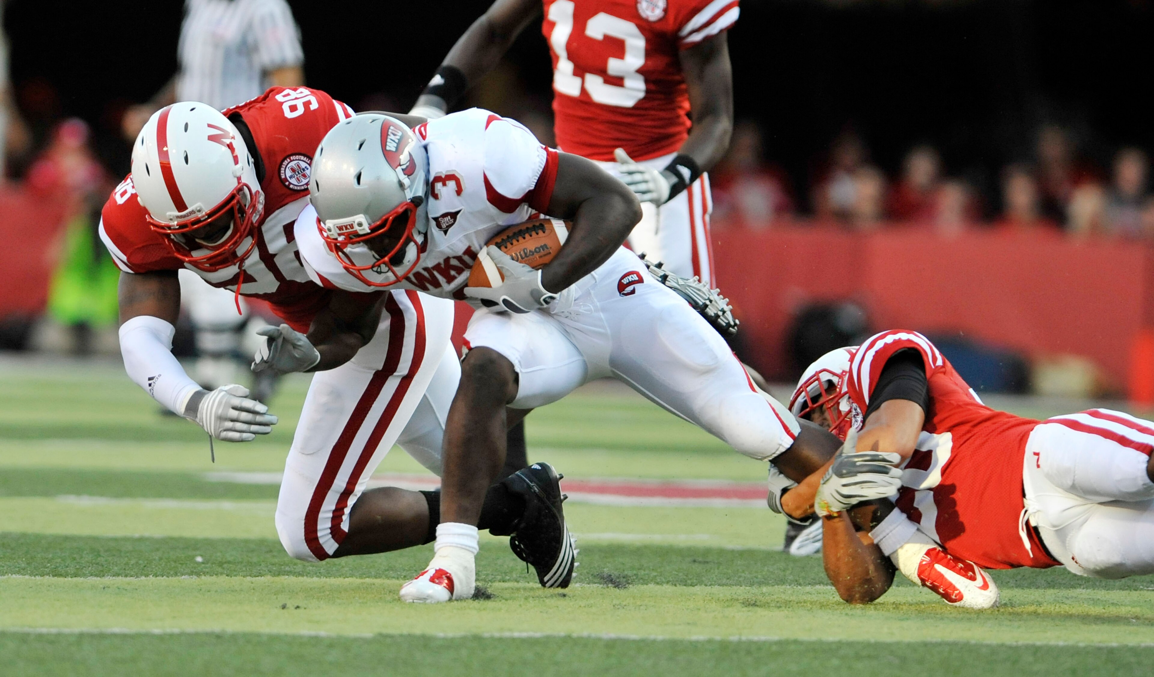 LINCOLN, NE - SEPTEMBER 04:  Bobby Rainey #3 of the Western Kentucky Hilltoppers gets brought down by Josh Williams #98 and Eric Hagg #28 of the Nebraska Cornhuskers during first half action of their game at Memorial Stadium on September 4, 2010 in Lincol
