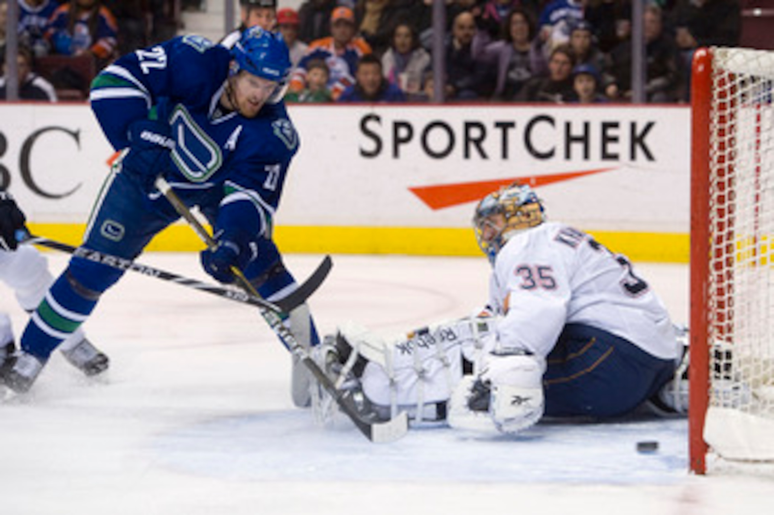VANCOUVER, CANADA - JANUARY 7: Daniel Sedin #22 of the Vancouver Canucks slides a backhand shot past goalie Nikolai Khabibulin #35 of the Edmonton Oilers for his second goal of the night during the second period at Rogers Arena January 7, 2011 in Vancouve