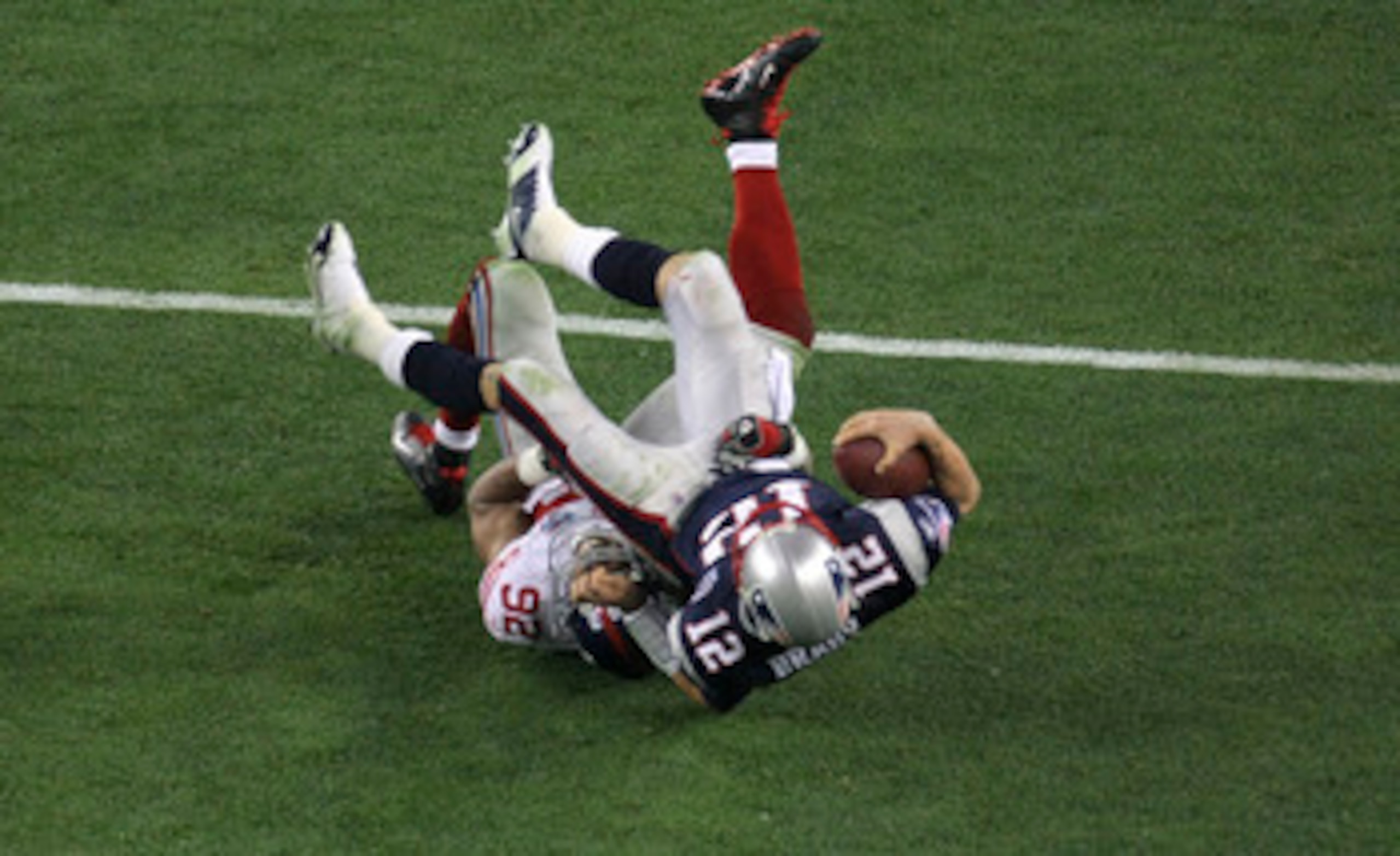 GLENDALE, AZ - FEBRUARY 03:  Quarterback Tom Brady #12 of the New England Patriots lies on his back after being sacked by defensive end Michael Strahan #92 of the New York Giants in the third quarter during Super Bowl XLII on February 3, 2008 at the Unive