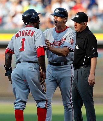 ATLANTA - JUNE 28:  Dan Radison #53 of the Washington Nationals holds back Nyjer Morgan #1 in the first inning from arguing with first base umpire James Hoye #92 (right) after being tagged out at first base against the Atlanta Braves at Turner Field on Ju