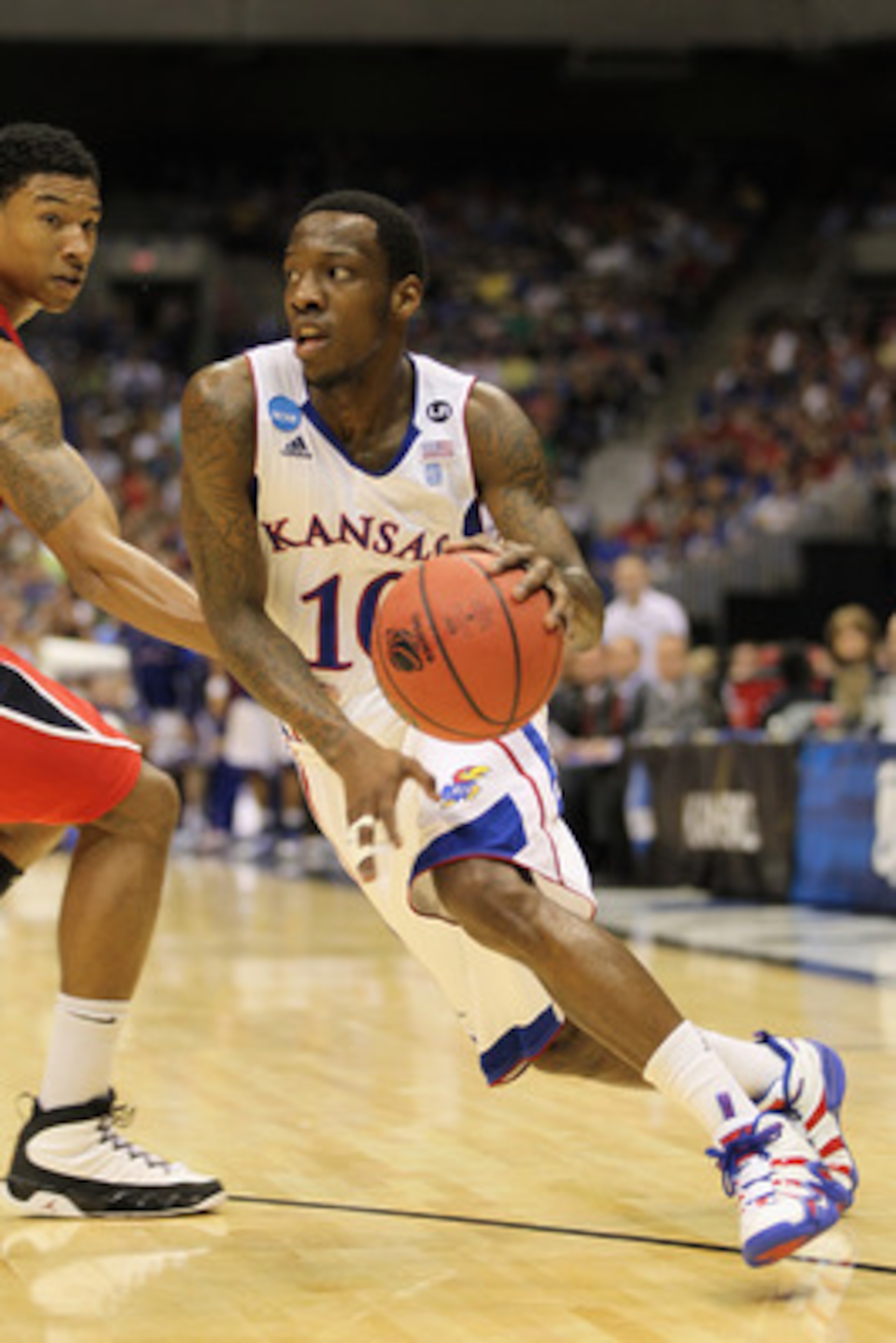 SAN ANTONIO, TX - MARCH 25:  Tyshawn Taylor #10 of the Kansas Jayhawks drives against Justin Harper #32 of the Richmond Spiders during the southwest regional of the 2011 NCAA men's basketball tournament at the Alamodome on March 25, 2011 in San Antonio, T