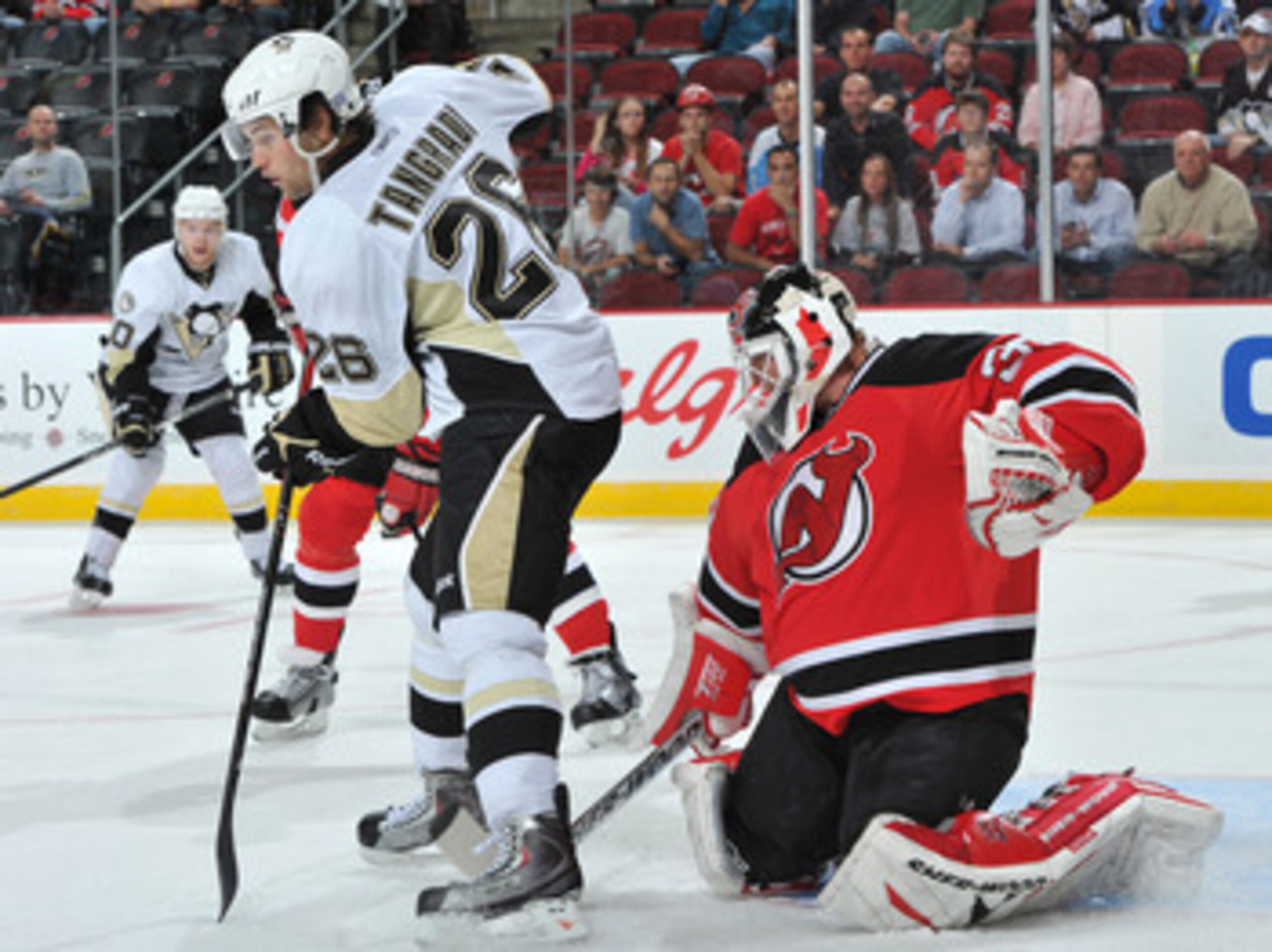 NEWARK, NJ - OCTOBER 11: Martin Brodeur #30 of the New Jersey Devils puts his stick between the legs of Eric Tangradi #26 of the Pittsburgh Penguins as he defends his net during the first period at the Prudential Center on October 11, 2010 in Newark, New