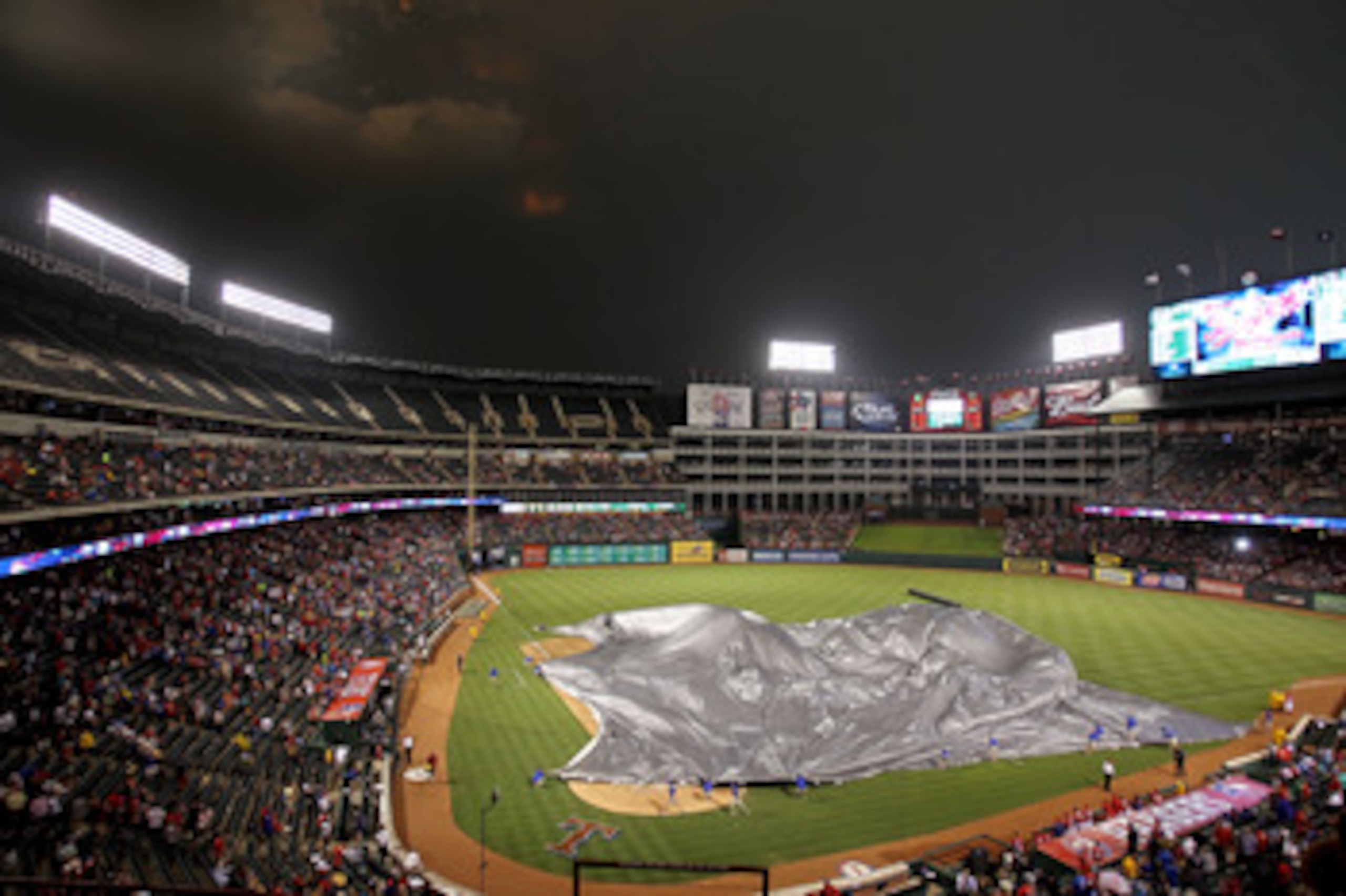 ARLINGTON, TX - MAY 24:  Workers cover the field at Rangers Ballpark in Arlington before a rain delay between the Chicago White Sox and Texas Rangers  on May 24, 2011 in Arlington, Texas.  (Photo by Ronald Martinez/Getty Images)