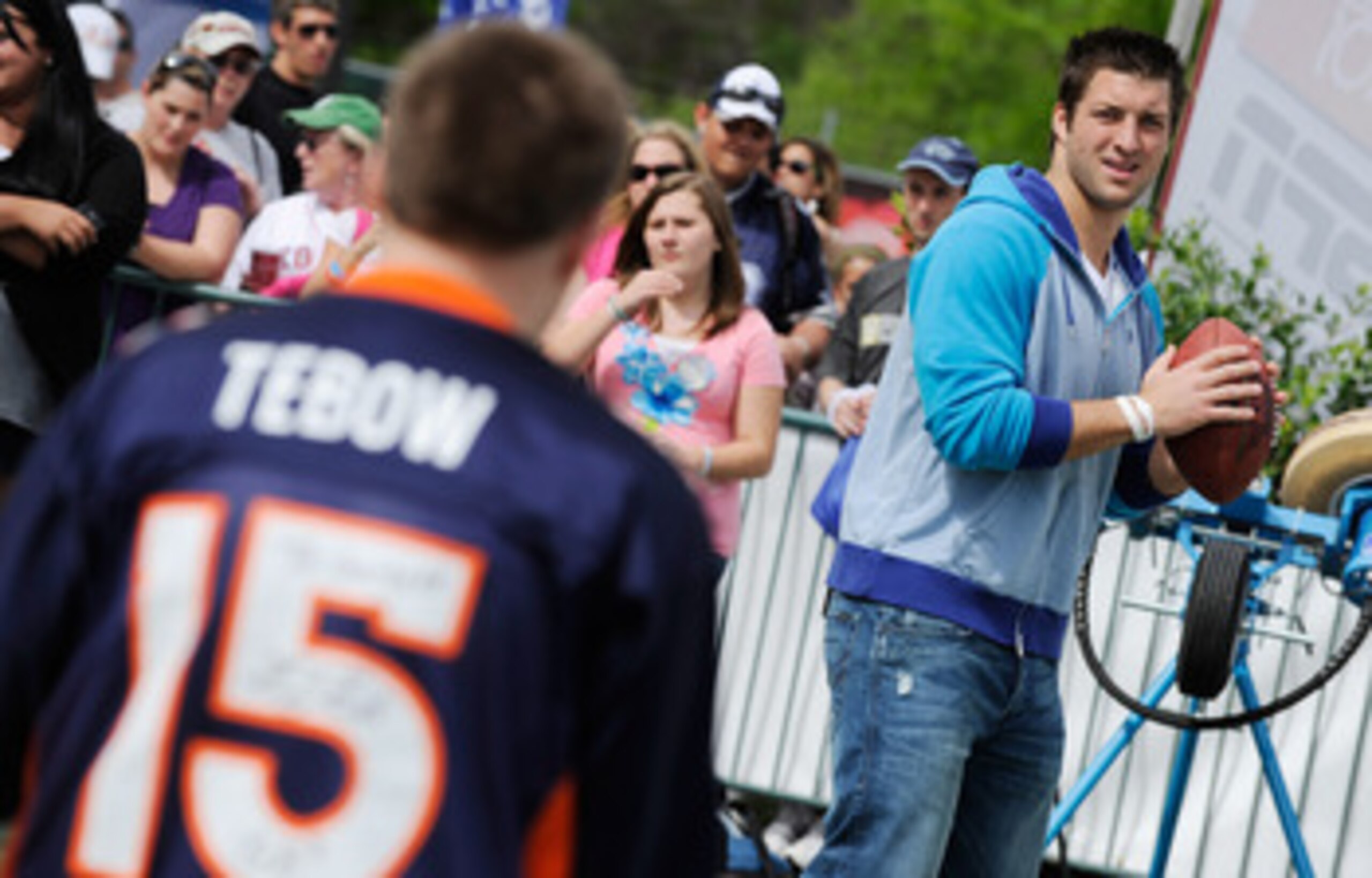 LAKE BUENA VISTA, FL - MAR 04: In this handout image provided by Disney Parks,  Denver Broncos quarterback Tim Tebow throws a football to a fan at Disney's Hollywood Studios park in Lake Buena Vista, Florida on March 4, 2011.   Tebow, a former Heisman Tro