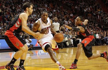 MIAMI, FL - JANUARY 22: Mario Chalmers #15 of the Miami Heat dribbles through DeMar DeRozan #10 and Jose Calderon #8 of the Toronto Raptors during a game at American Airlines Arena on January 22, 2011 in Miami, Florida. NOTE TO USER: User expressly acknow