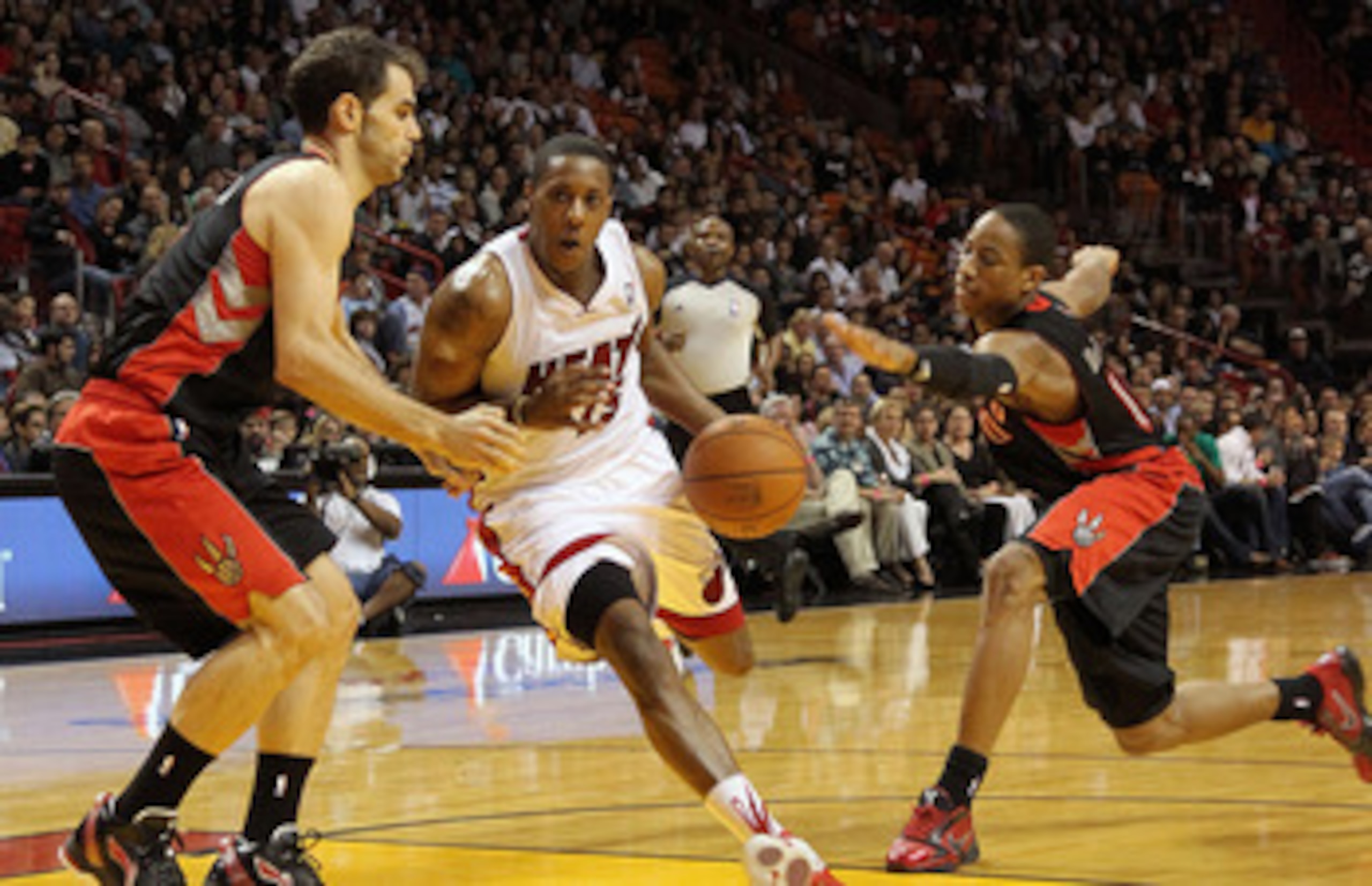 MIAMI, FL - JANUARY 22: Mario Chalmers #15 of the Miami Heat dribbles through DeMar DeRozan #10 and Jose Calderon #8 of the Toronto Raptors during a game at American Airlines Arena on January 22, 2011 in Miami, Florida. NOTE TO USER: User expressly acknow