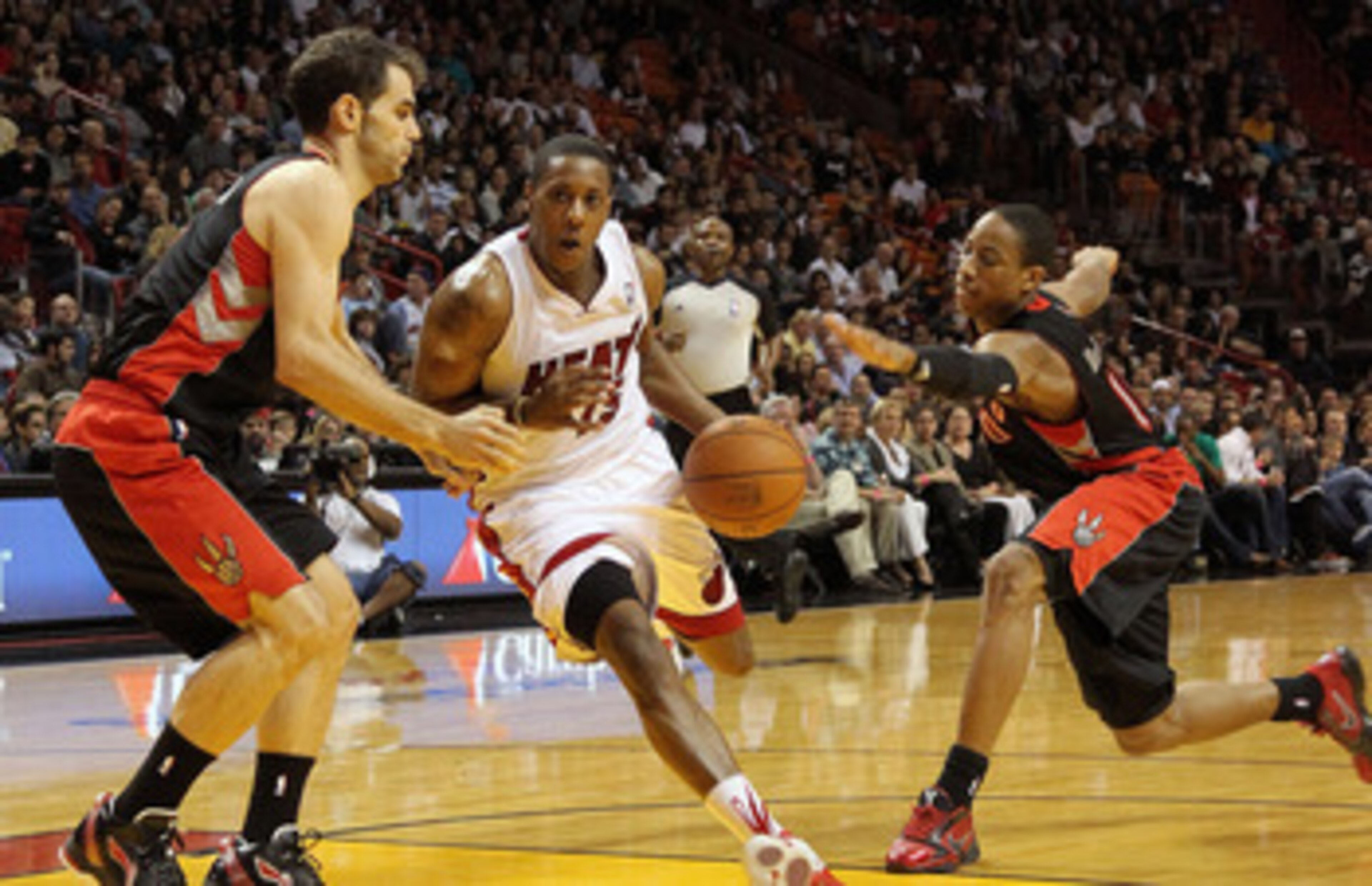 MIAMI, FL - JANUARY 22: Mario Chalmers #15 of the Miami Heat dribbles through DeMar DeRozan #10 and Jose Calderon #8 of the Toronto Raptors during a game at American Airlines Arena on January 22, 2011 in Miami, Florida. NOTE TO USER: User expressly acknow MIAMI, FL - JANUARY 22: Mario Chalmers #15 of the Miami Heat dribbles through DeMar DeRozan #10 and Jose Calderon #8 of the Toronto Raptors during a game at American Airlines Arena on January 22, 2011 in Miami, Florida. NOTE TO USER: User expressly acknow